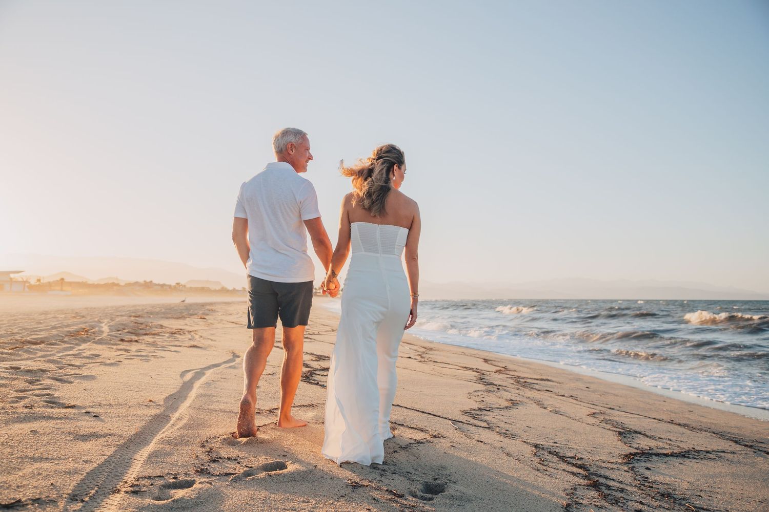 Romantic beach walk at sunset with ocean waves in the background.