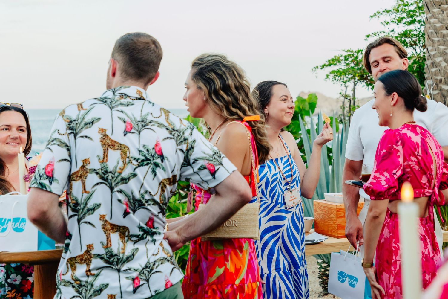 A group of people enjoying a lively outdoor party with tropical decor and colorful attire.