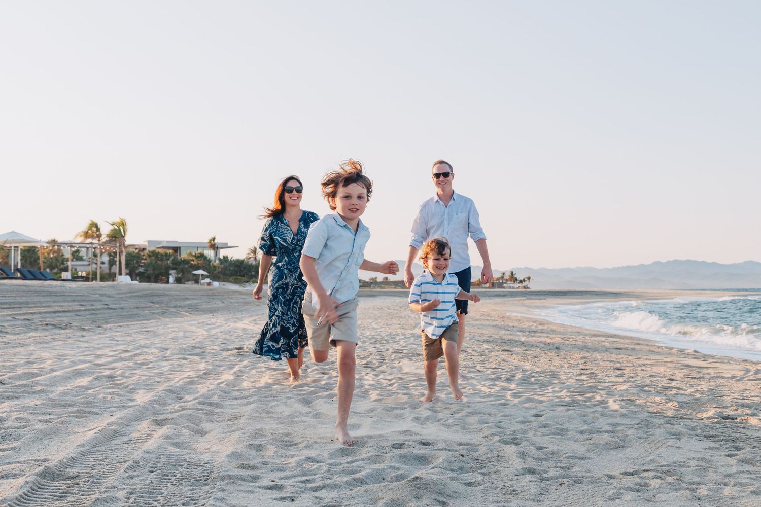 People enjoying a relaxing afternoon walk along a pristine sandy beach with ocean waves.