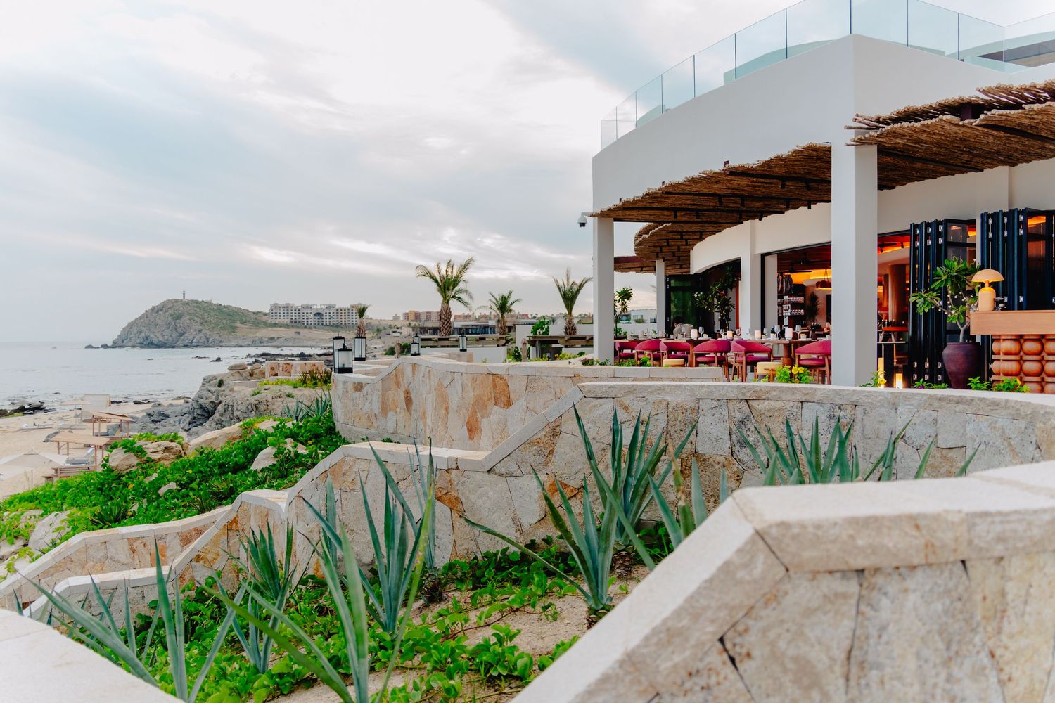 Panoramic coastal view of a Mexican beach town with white buildings nestled along the hillside overlooking the ocean.
