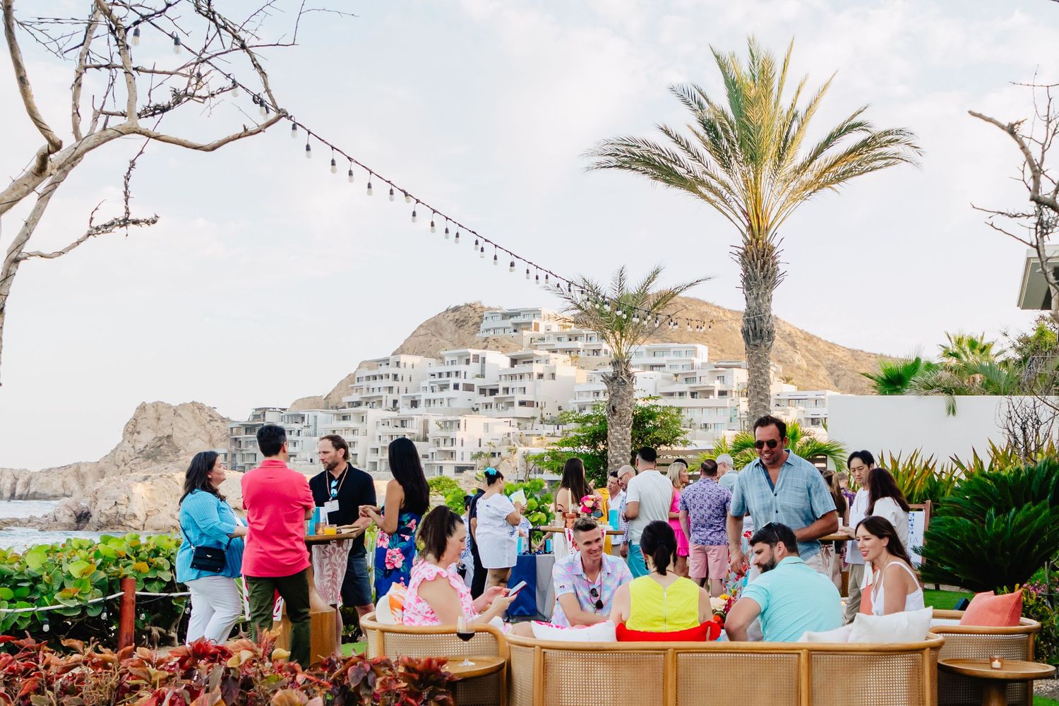 People enjoy a scenic coastal view with palm trees and mountains at a beachfront resort in Agadir, Morocco.