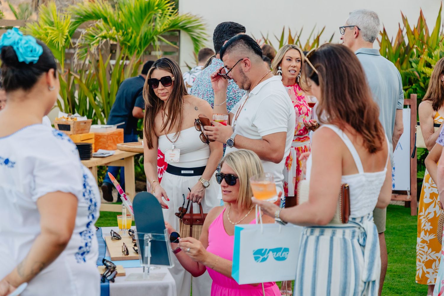 Attendees enjoying cocktails and conversation at a tropical outdoor reception.