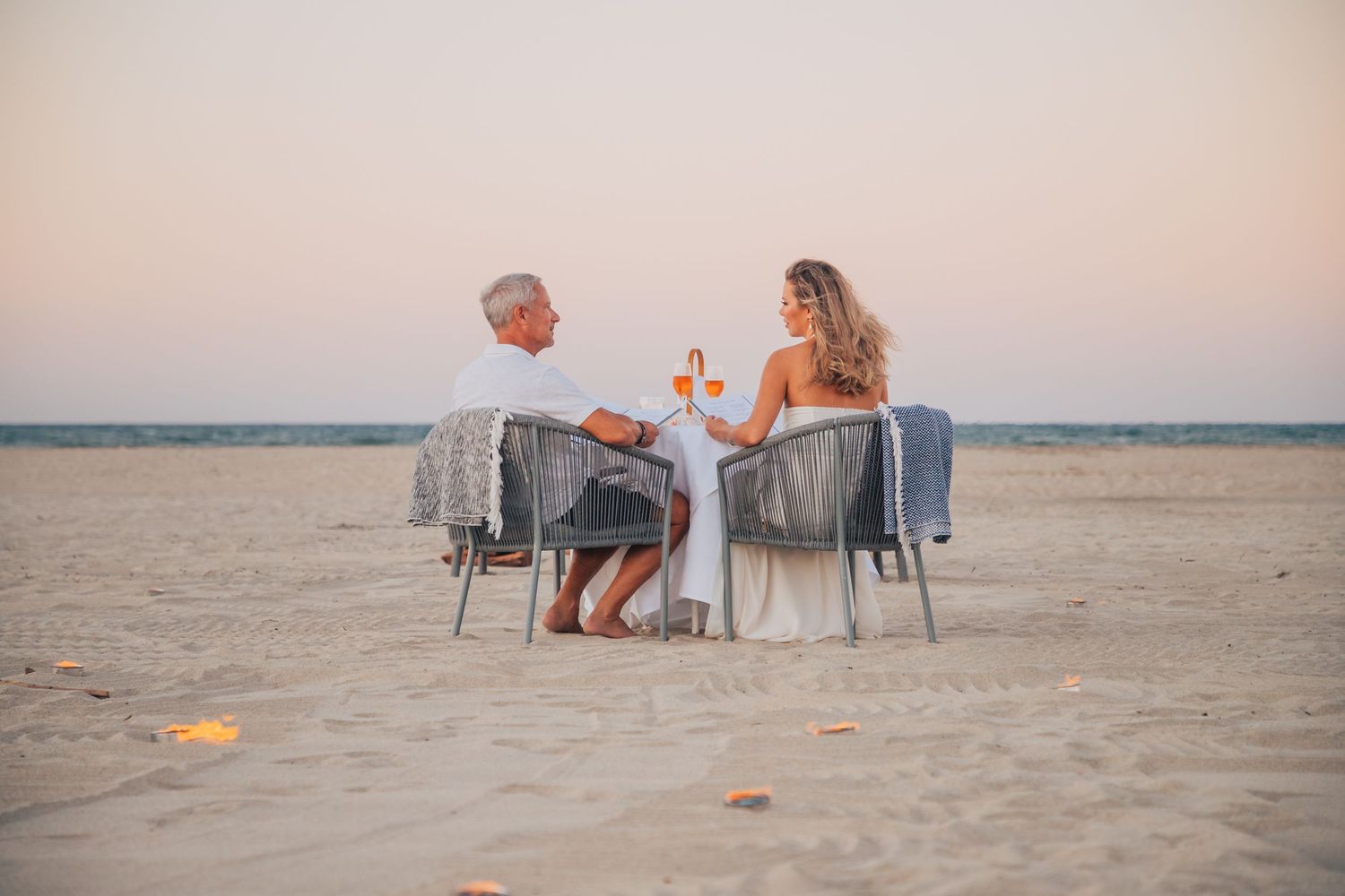 Couple enjoying a romantic beach picnic setup during sunset.