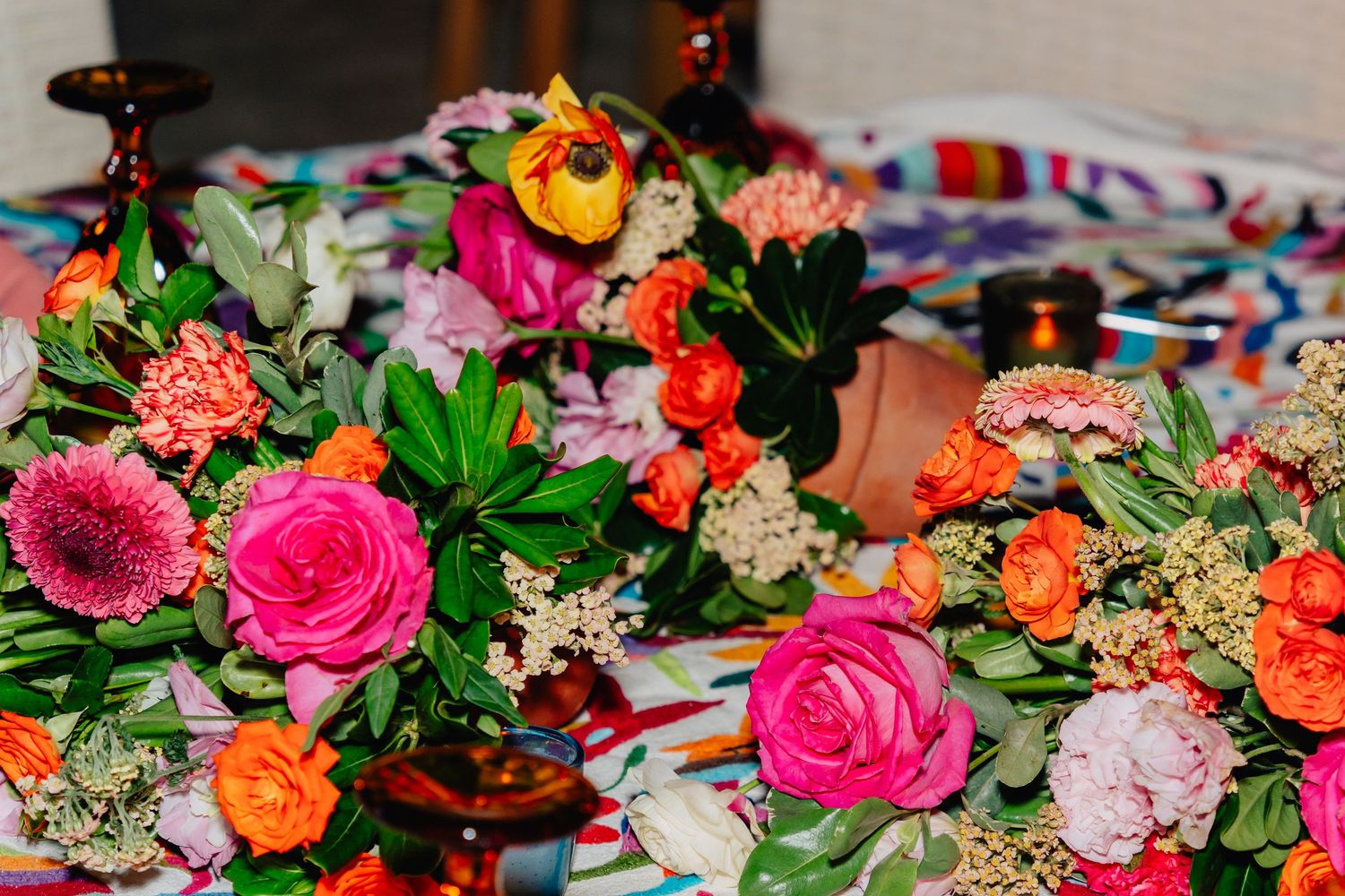 Vibrant floral arrangement featuring pink roses, orange ranunculus, and white flowers on a table setting.
