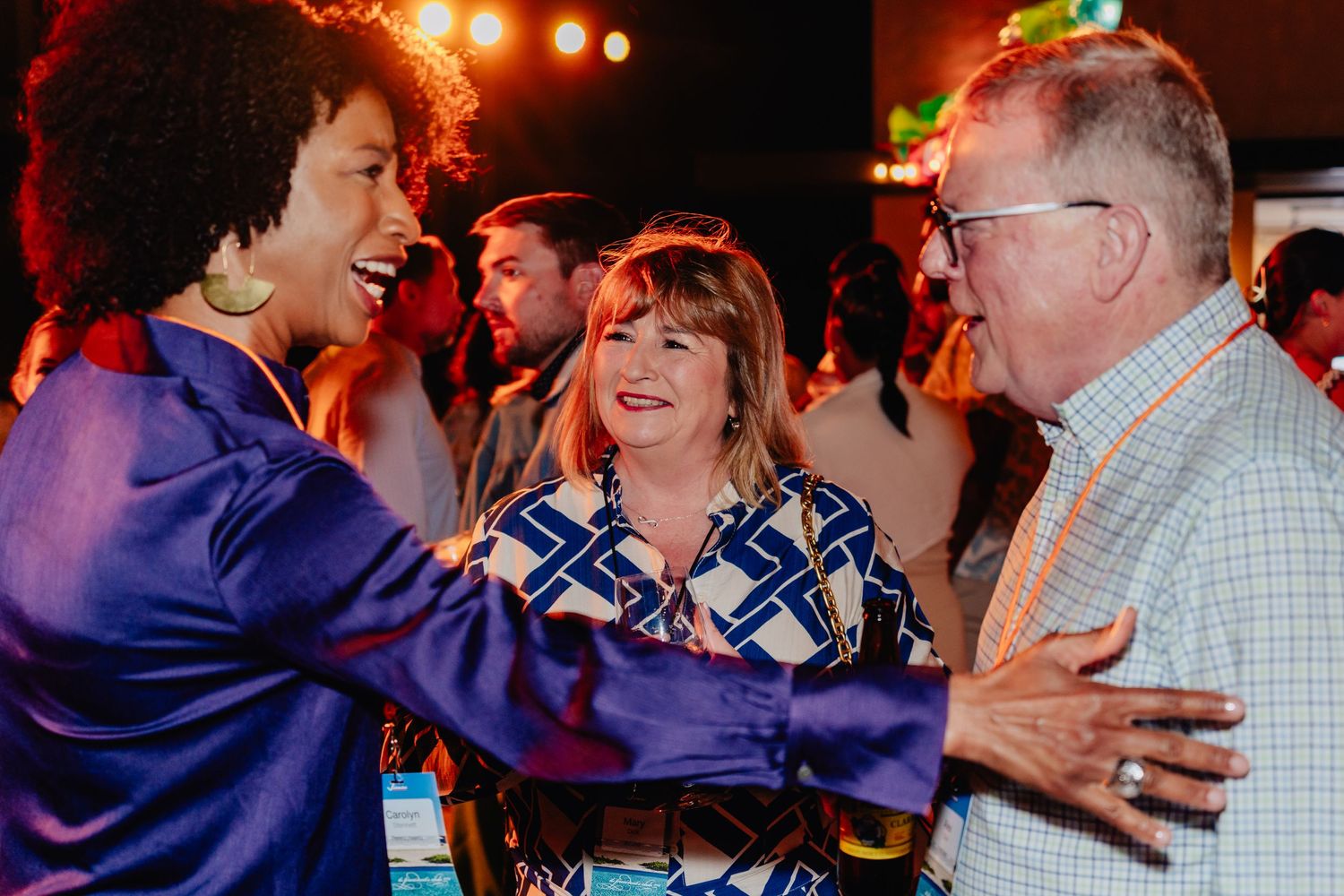 People dancing and laughing together at a social event with warm lighting and festive atmosphere.