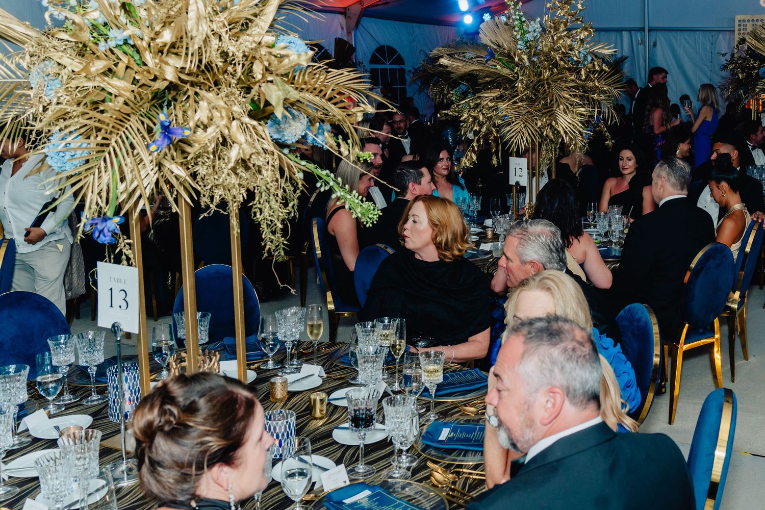 Elegant banquet hall decorated with palm fronds and blue lighting for an evening celebration.