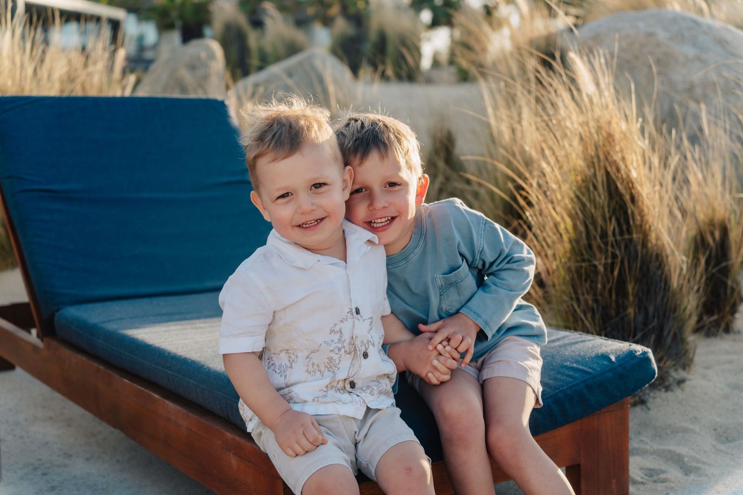 Two children share a happy moment together on a blue outdoor lounge chair.