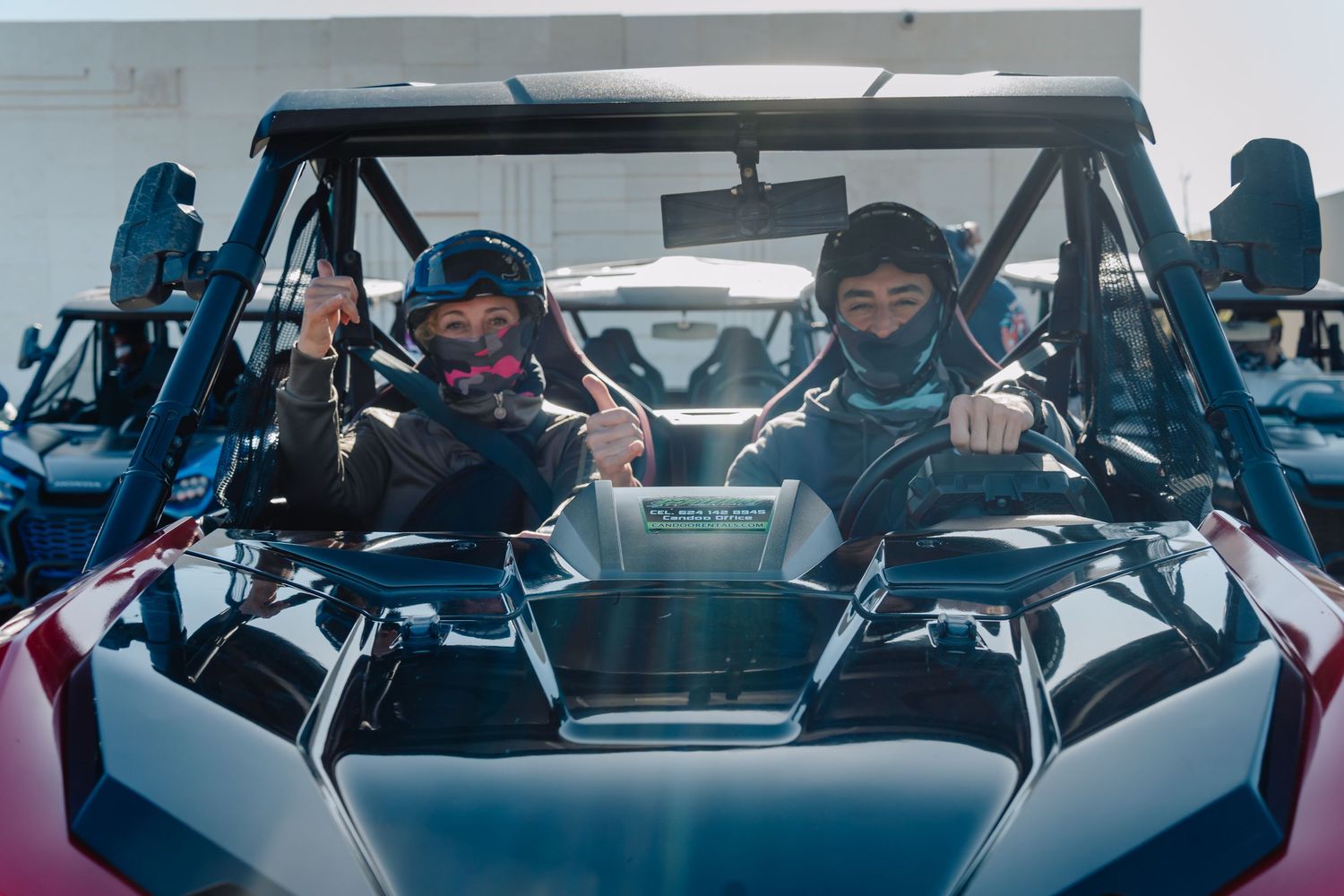 Two people wearing winter gear sit in a sleek Polaris snowmobile with blue tinted lighting.