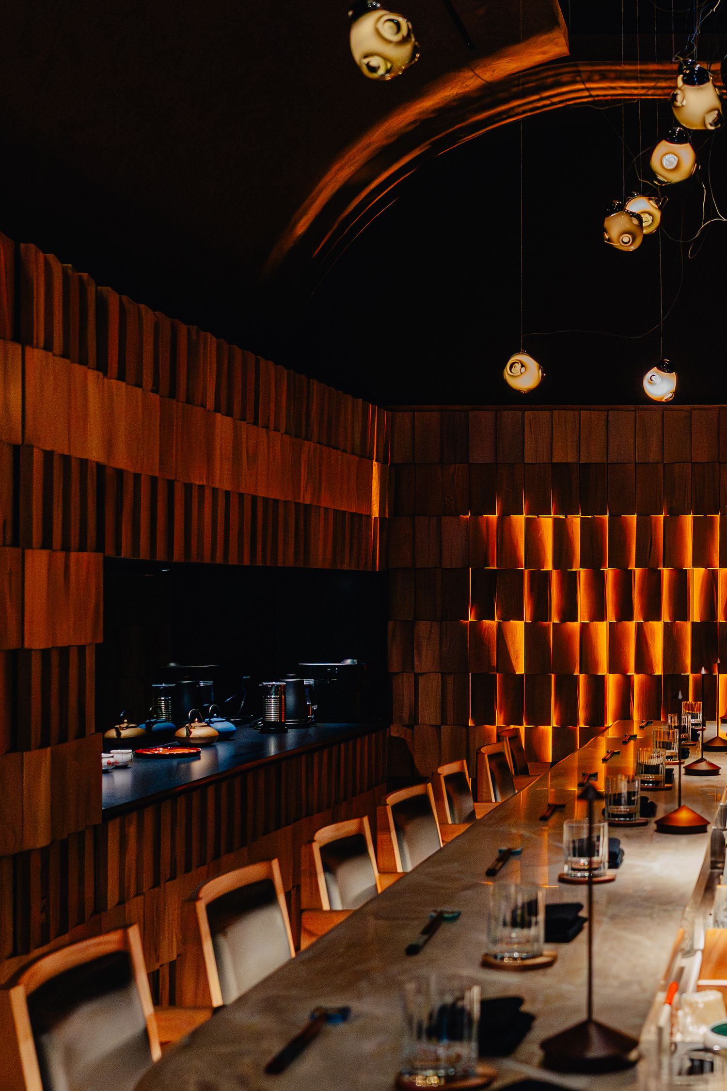 Elegant Japanese restaurant interior with wooden wall panels and lantern lighting along a modern dining counter.