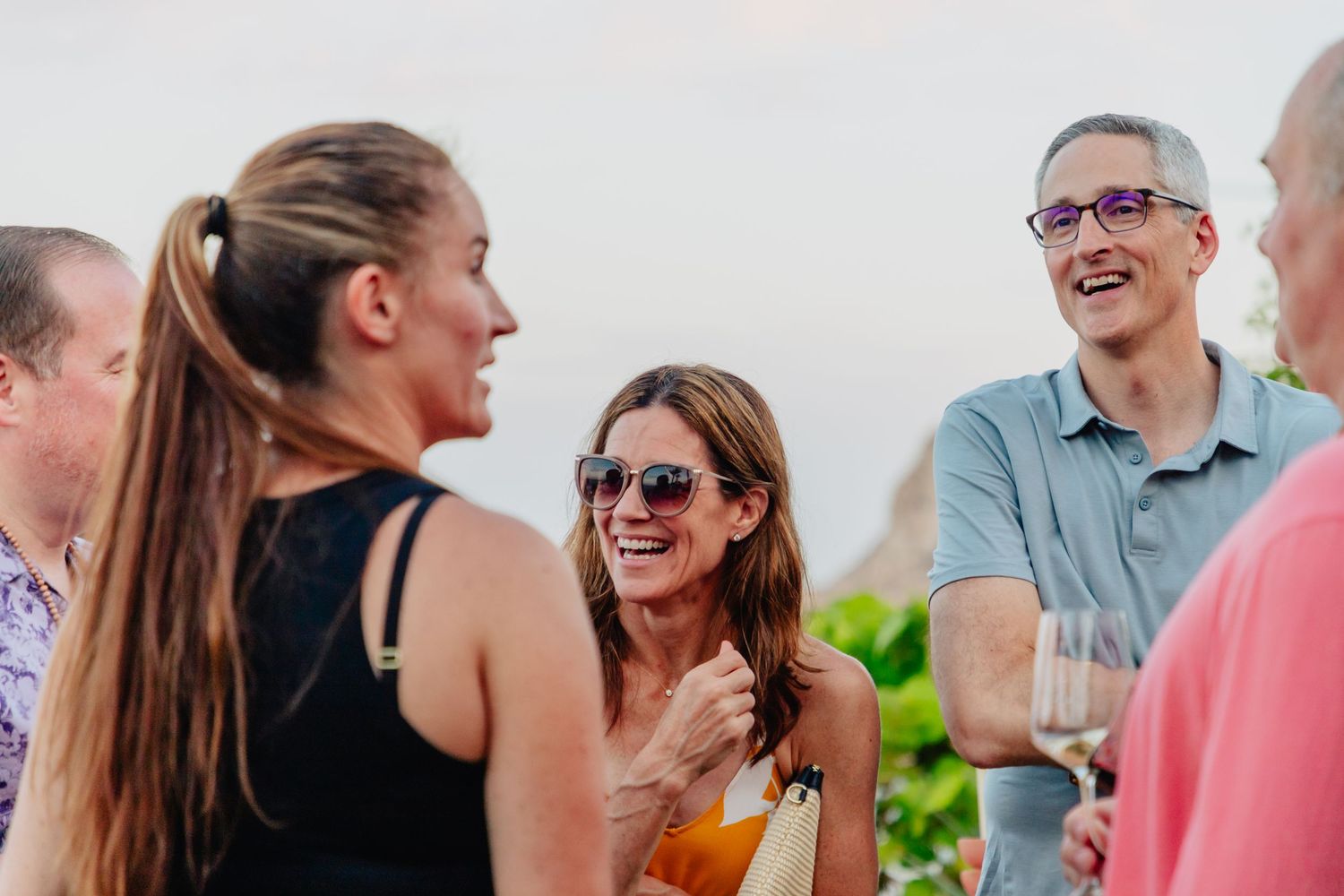 A group of people laughing and socializing together outdoors during a casual gathering.