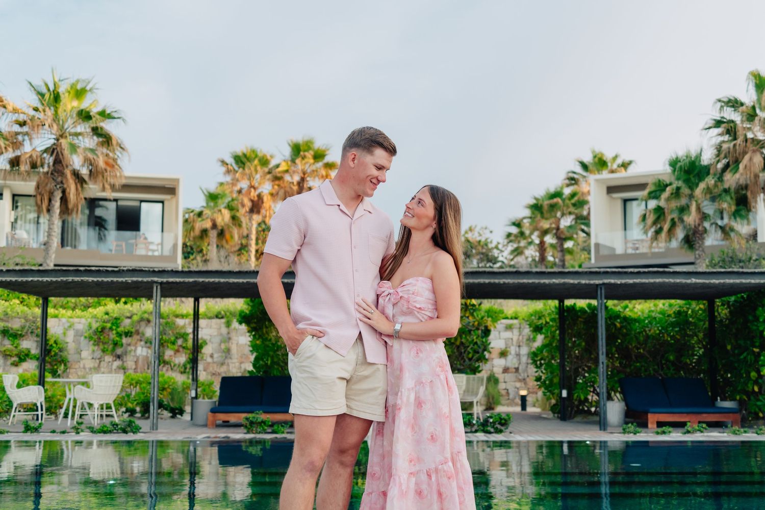 A group poses against a tropical backdrop with palm trees and modern architecture.