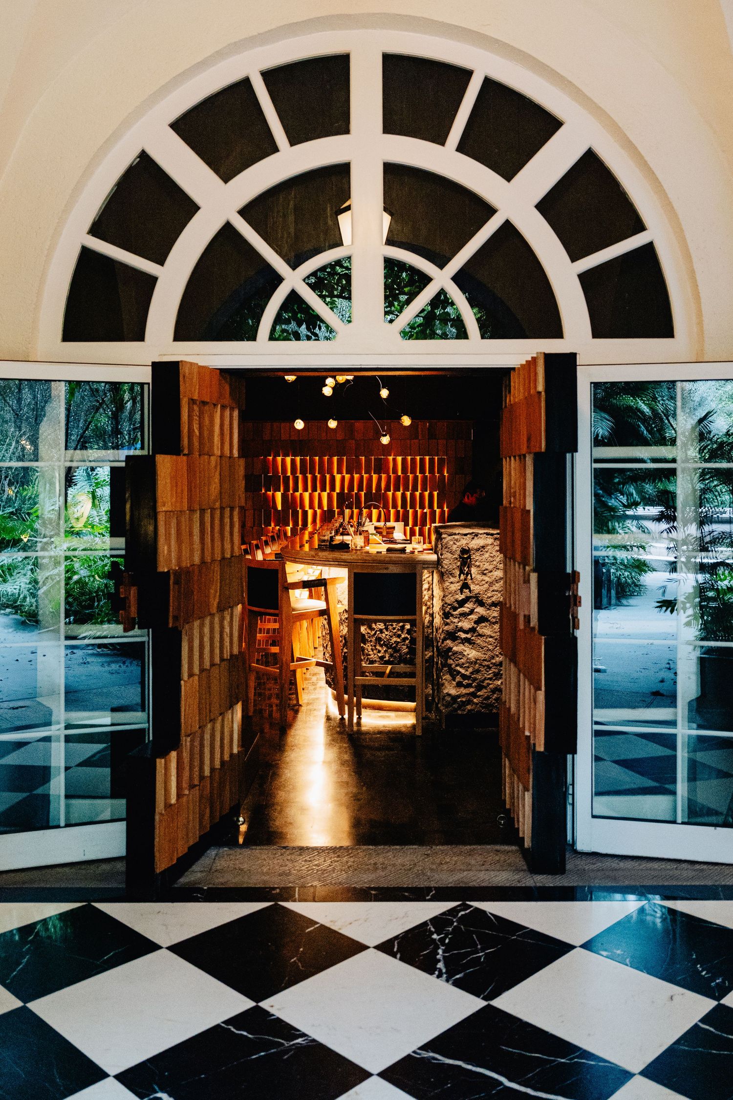 A modern venue entrance with arched windows, checkered marble floors and warm lighting creates an elegant atmosphere.
