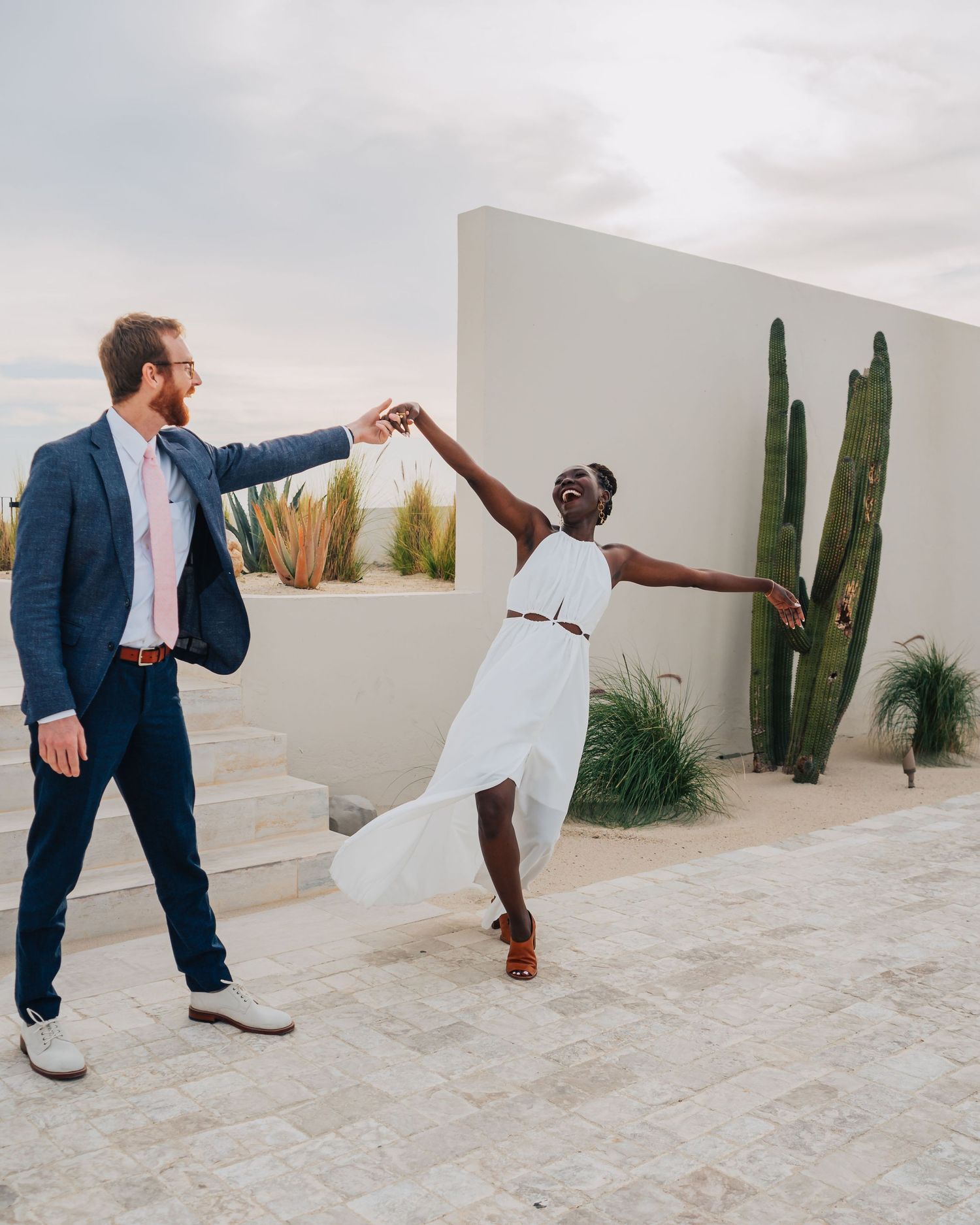 Modern desert photoshoot with white walls and cactus showing dynamic dance-like poses and movements.