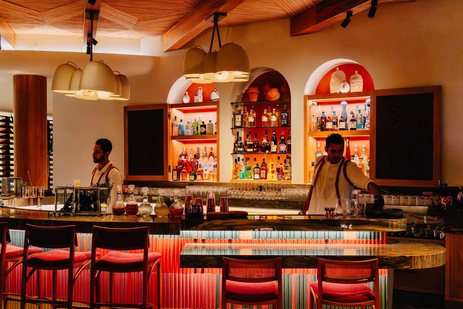 Modern bar interior with red bar stools and warm lighting showcases sleek design and well-stocked shelves.