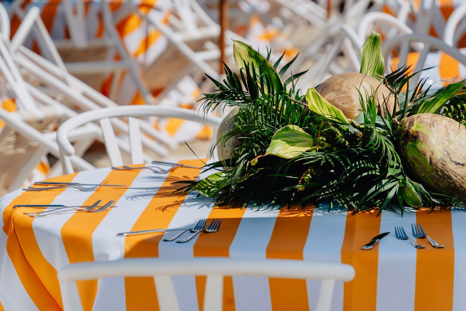 Close-up of orange and white striped party decorations with greenery accents.