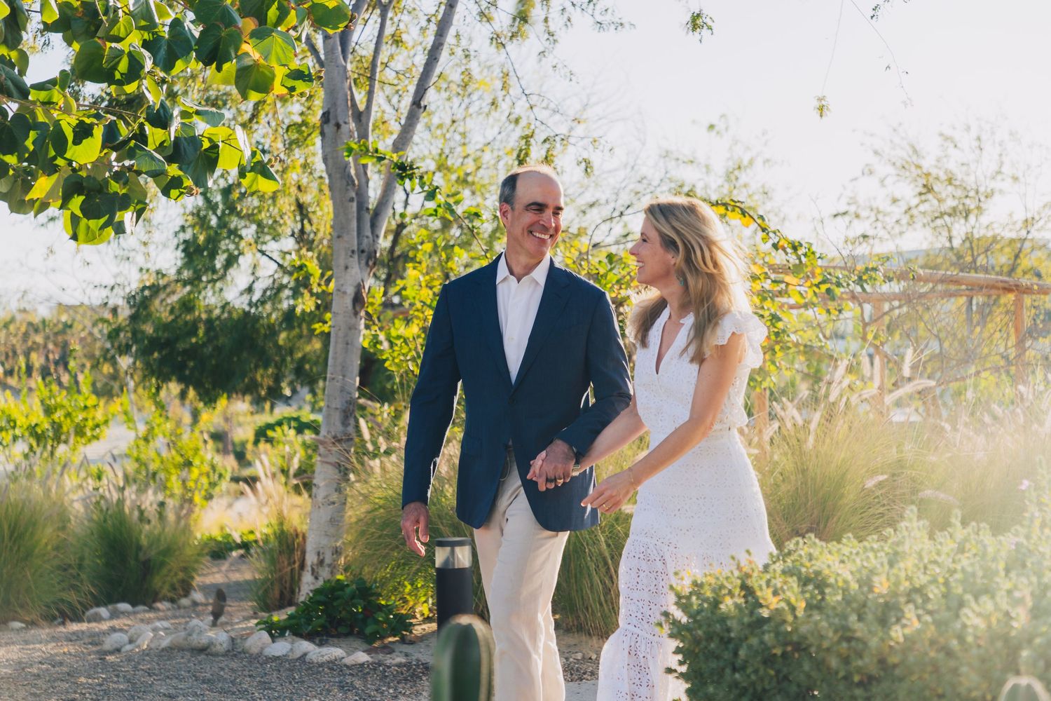 Romantic couple embraces in golden sunlight among yellow leaves and trees in a natural outdoor setting.