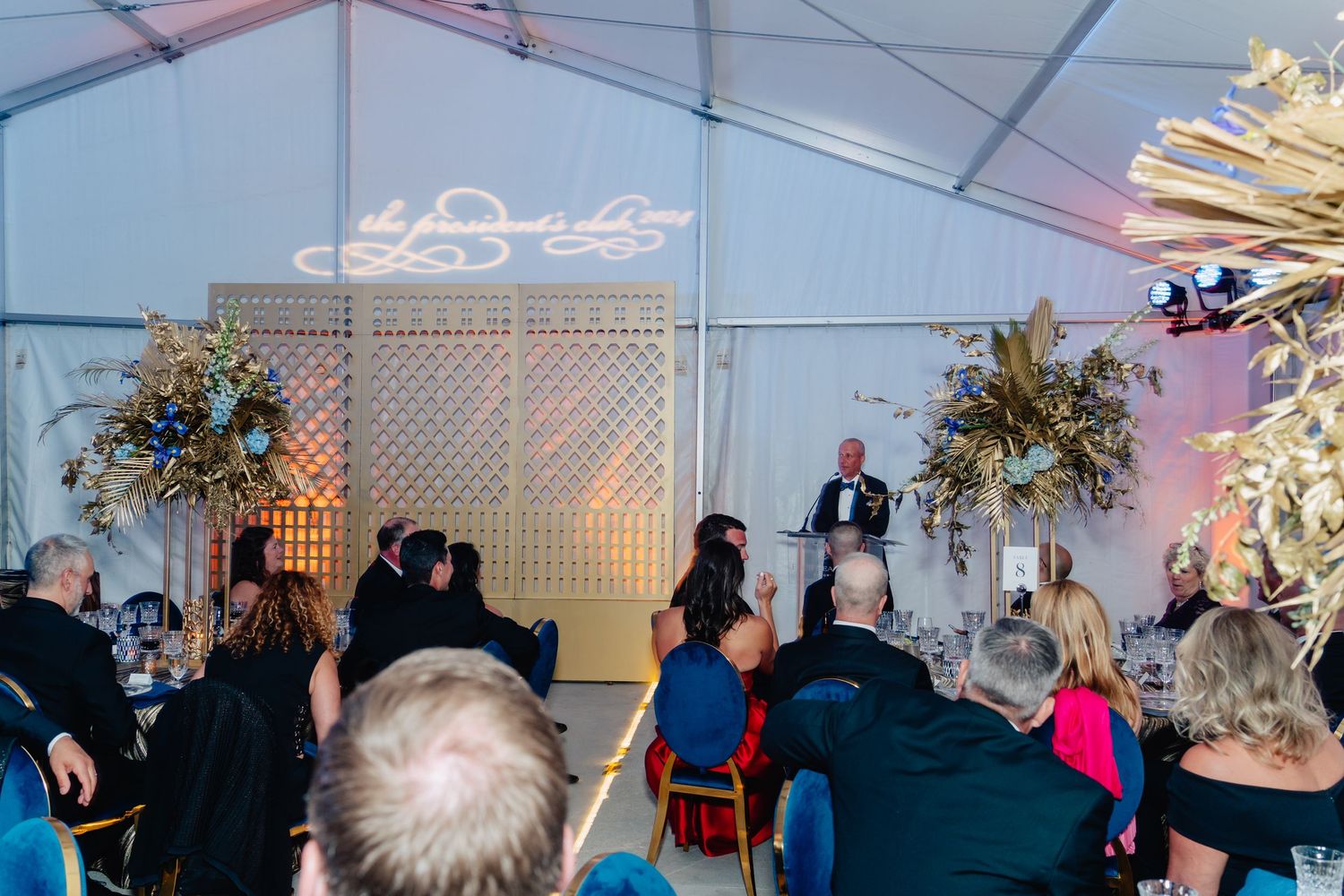 Large white event tent interior decorated for an elegant celebration with guests seated at tables.