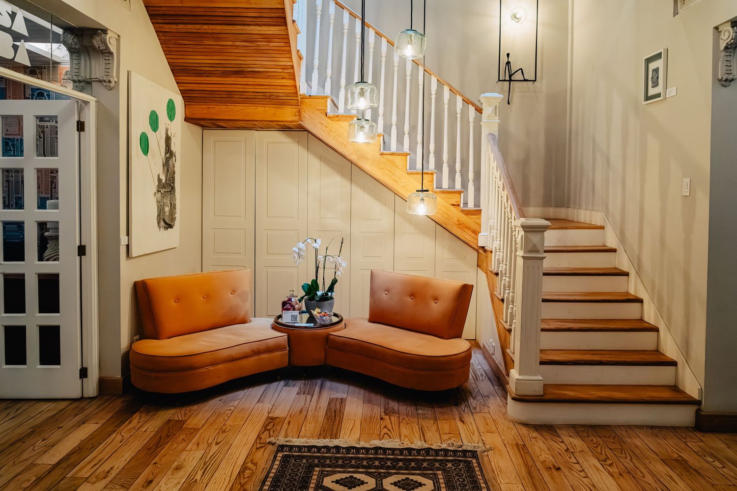 Modern staircase with wooden treads and white risers leading upstairs in bright hallway with hardwood flooring.