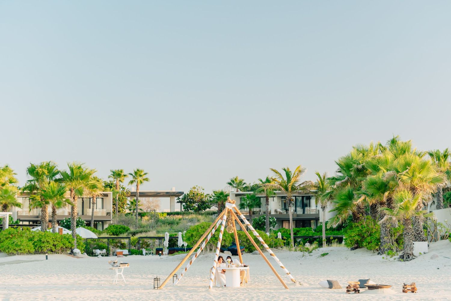 Tropical beach resort setting with palm trees and elegant event setup.