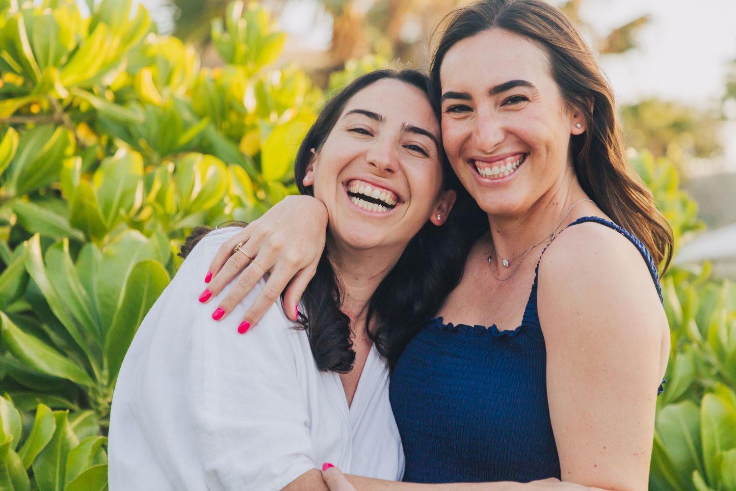 Two friends sharing joyful laughter among tropical foliage.