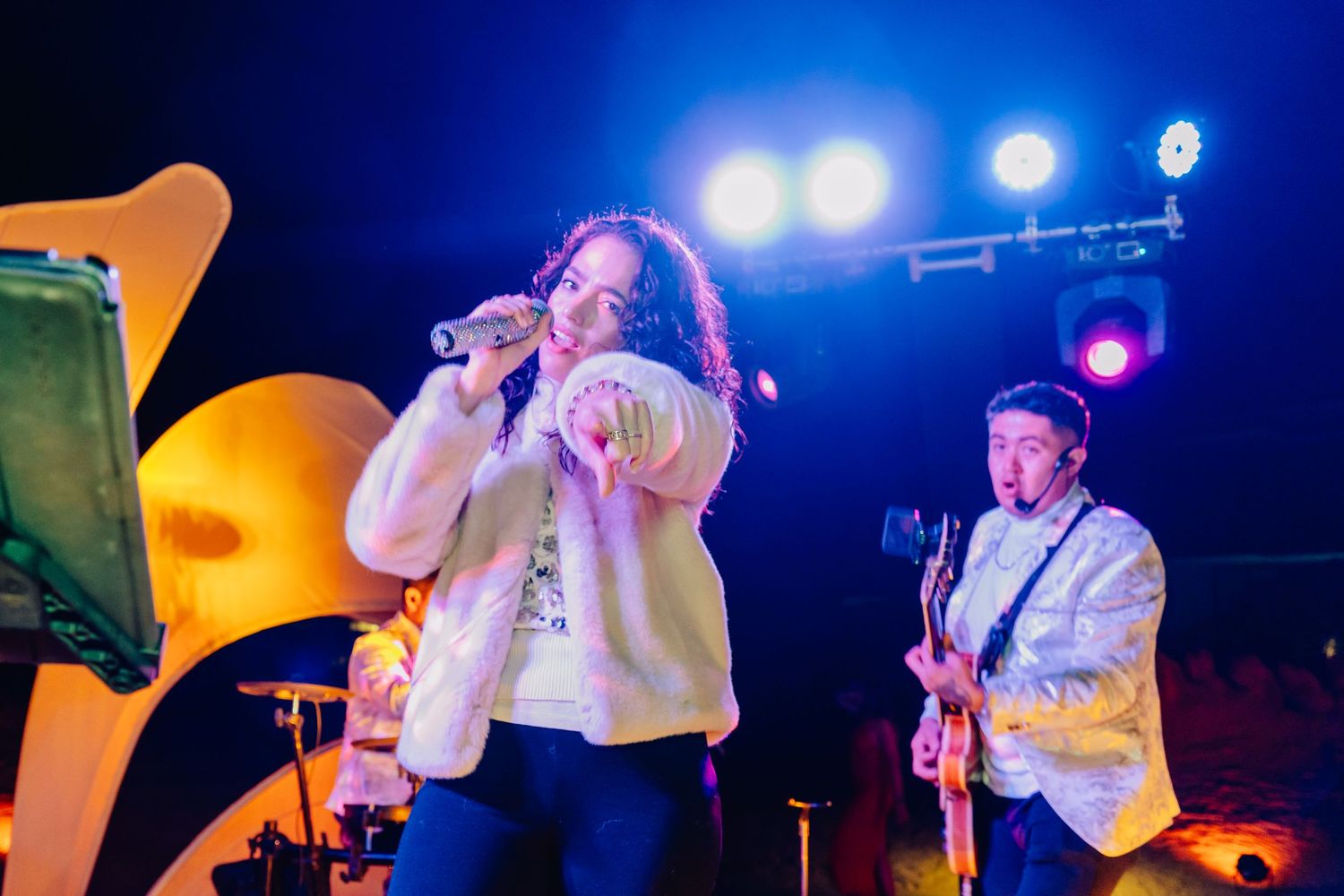 Band performs on stage with dramatic blue and orange concert lighting effects.
