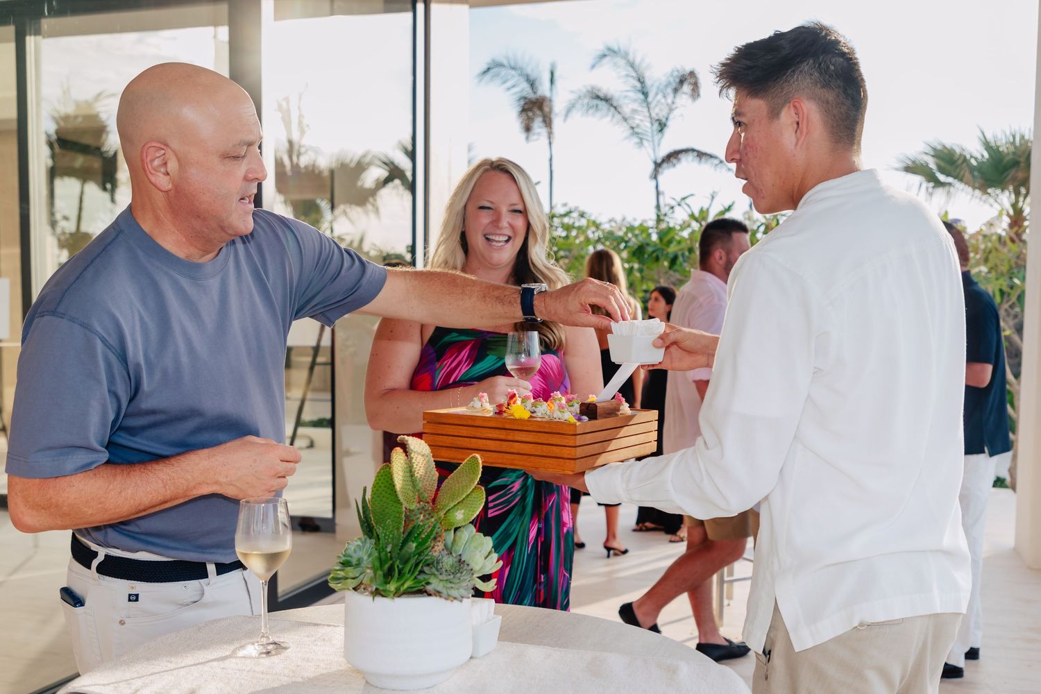 Guests enjoying drinks and appetizers at an outdoor coastal event.