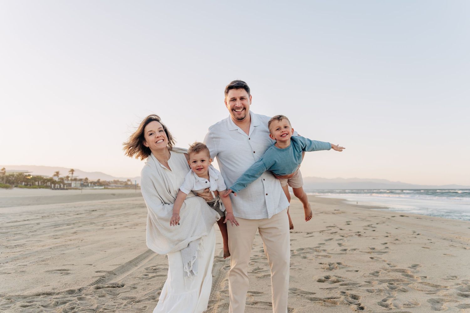 A joyful family enjoying themselves on a beach at sunset.