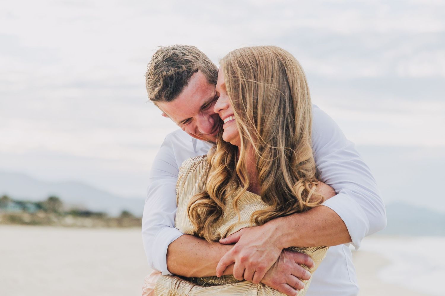 Tender moment captured between couple during beach engagement.