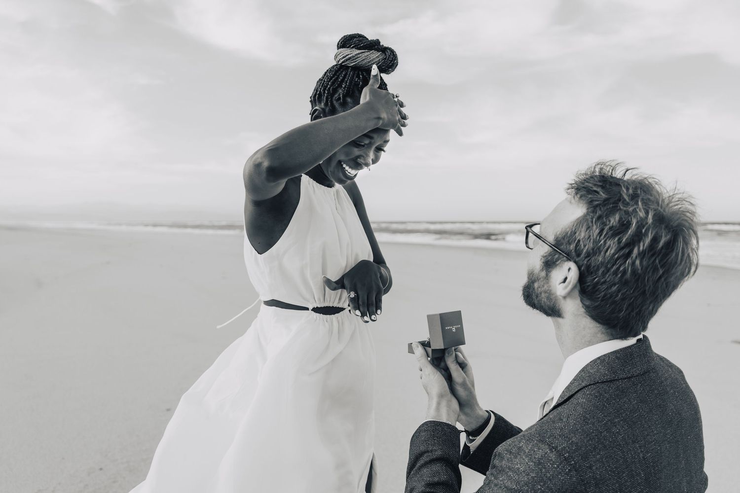 Black and white candid moments of beach proposal celebration.