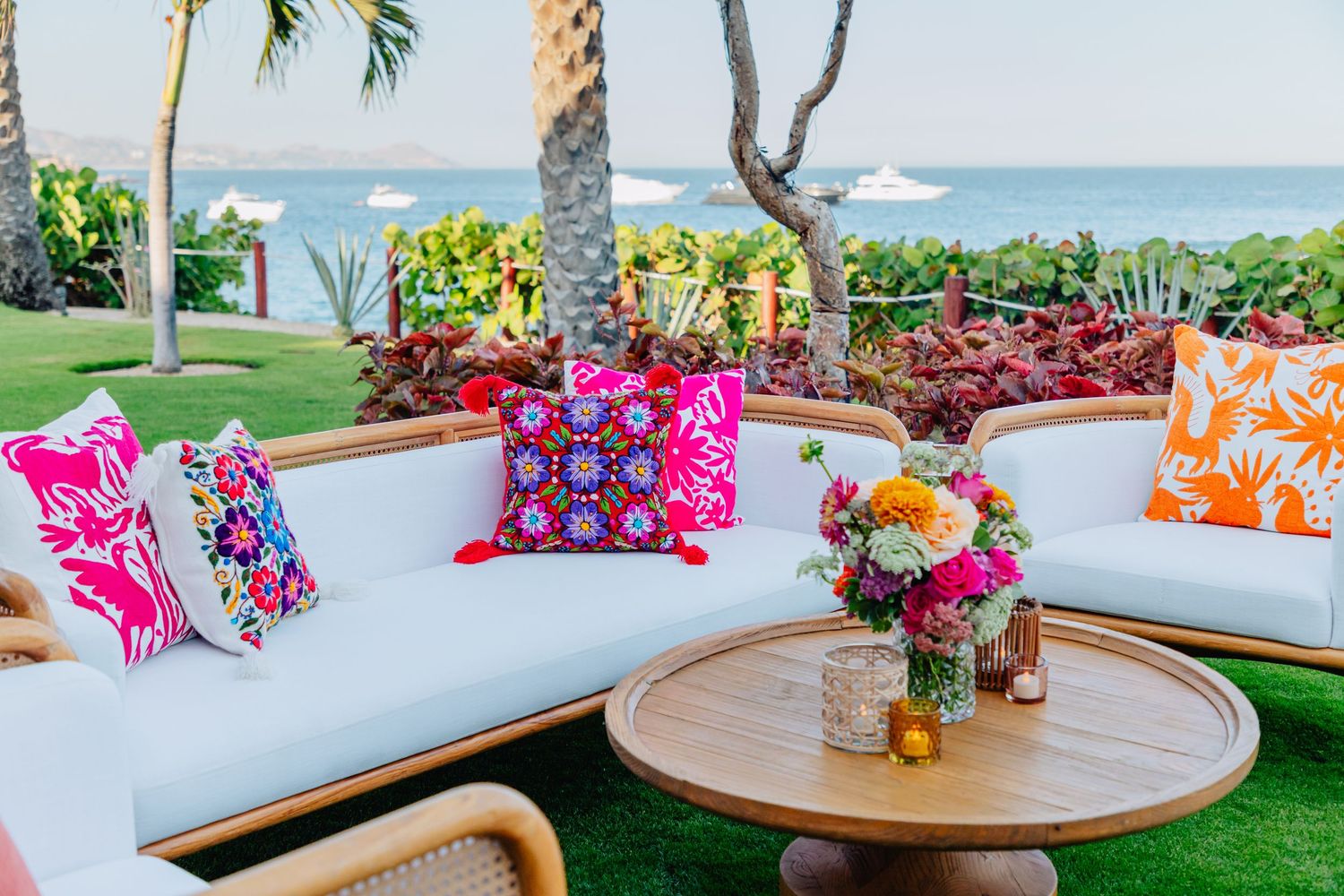 Colorful outdoor lounge area with vibrant throw pillows and cushioned seating overlooking a tropical ocean view.