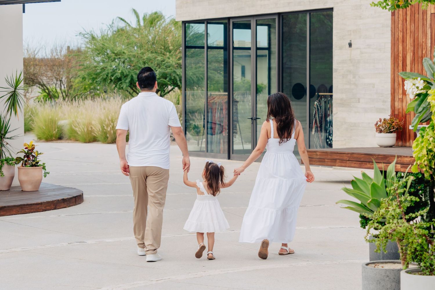A series of five connected photos showing people walking in white dresses along a modern building exterior.