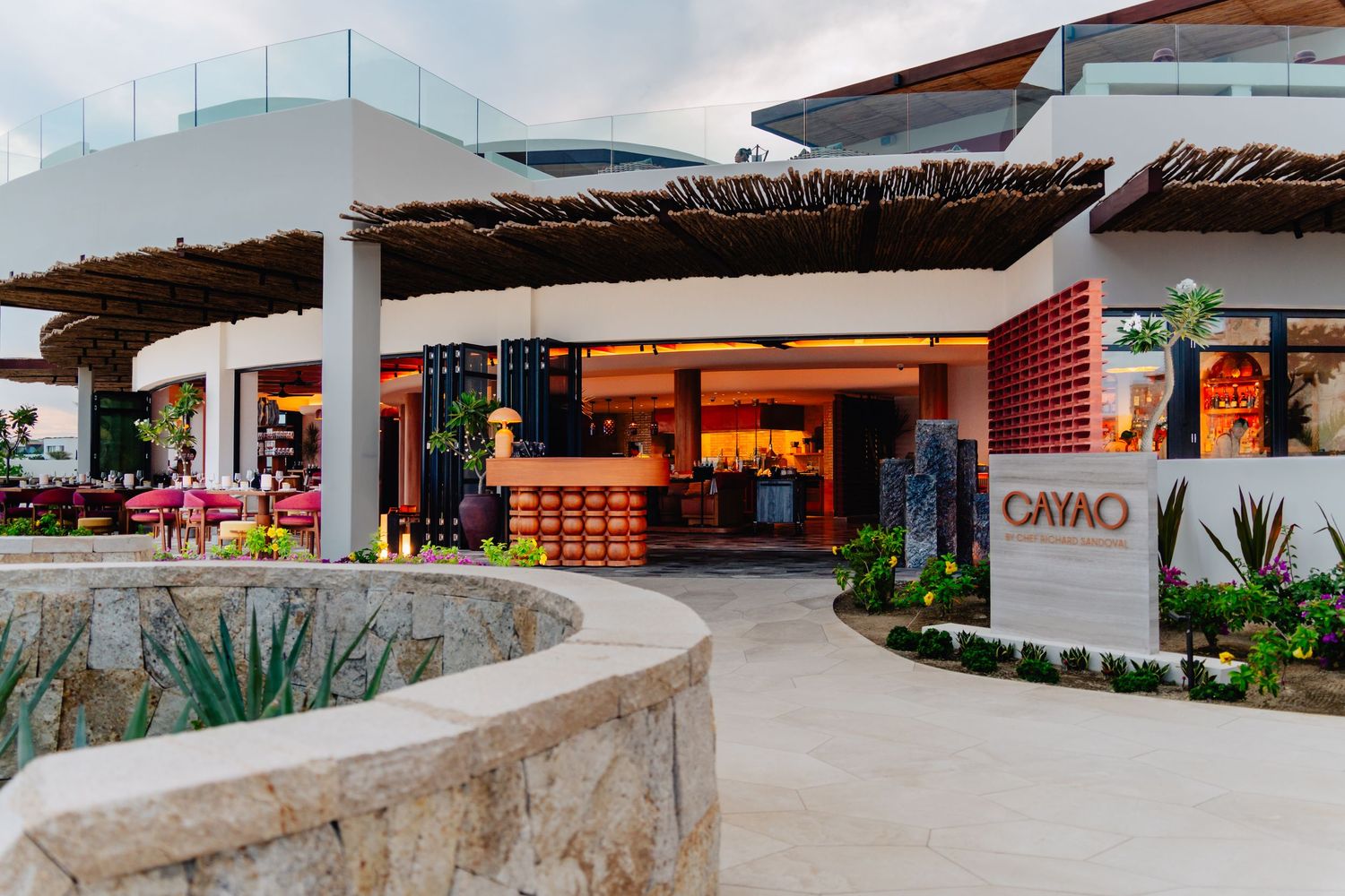 Exterior view of Cayao restaurant entrance with thatched roof and modern design elements.