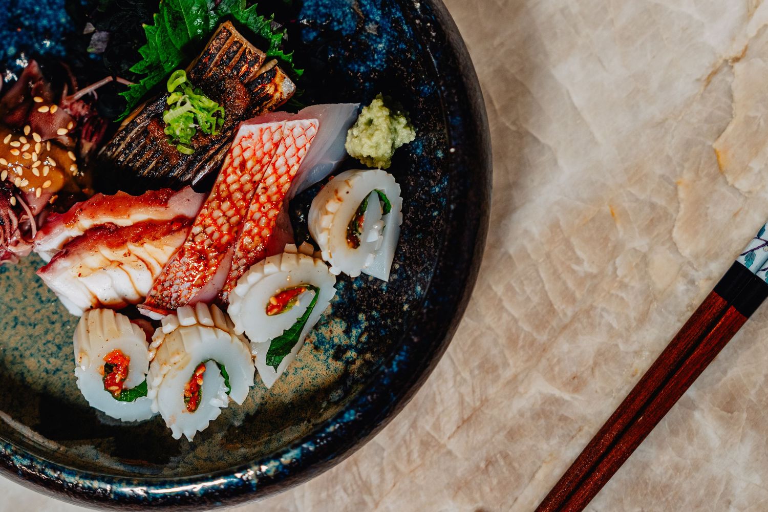 Beautifully plated sushi and sashimi dishes arranged on dark plates against a light background.
