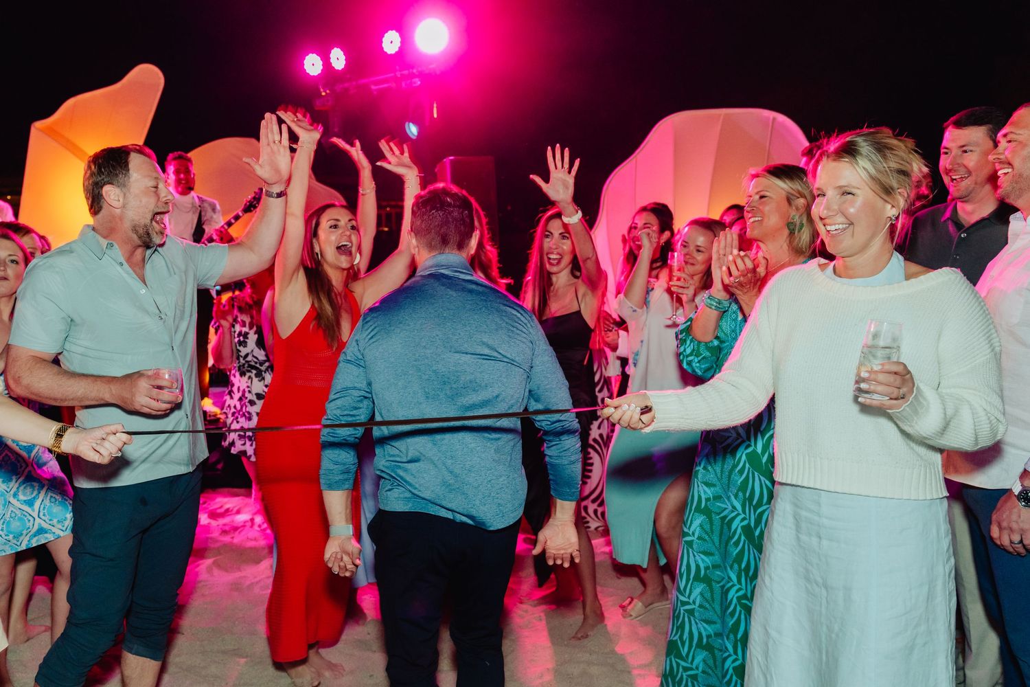 Lively dance party with colorful pink lighting and a crowd of people dancing.