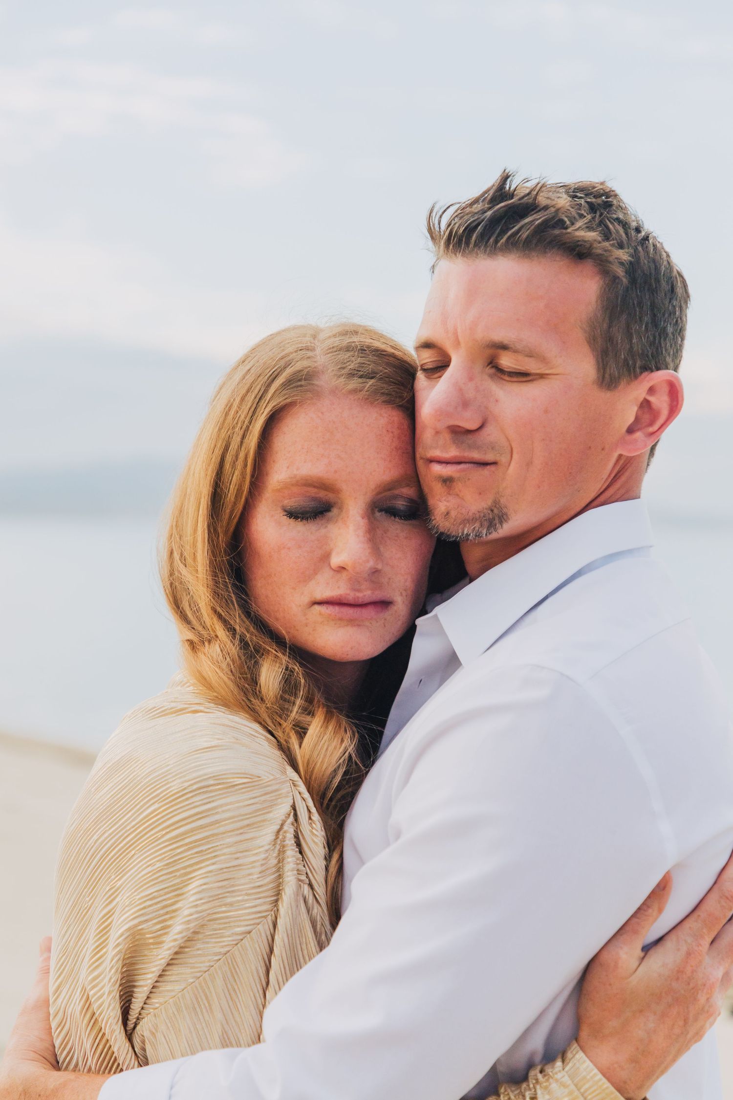 Romantic embrace on beach with soft natural lighting.