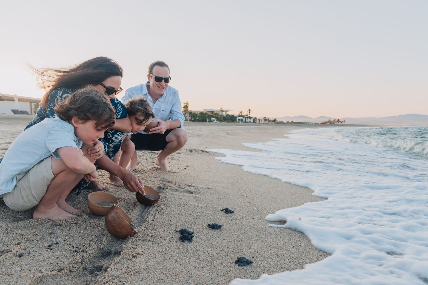 Small group gathered on a beach near the water's edge during golden hour.