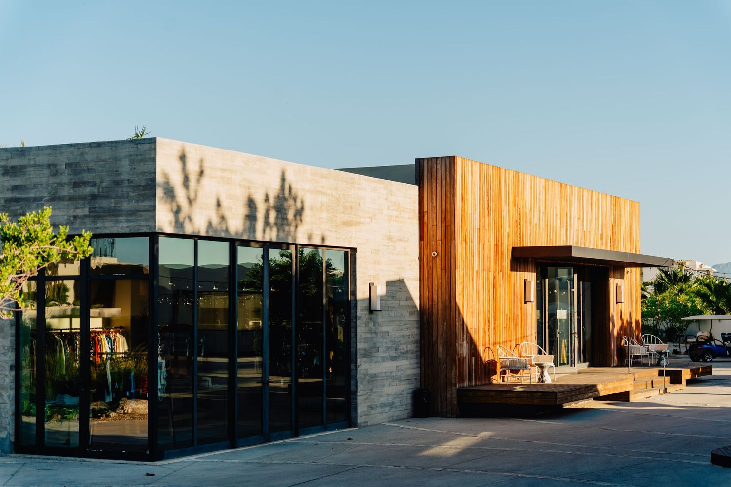 Modern commercial building exterior with wooden accents and glass walls reflecting sunlight in an urban setting.