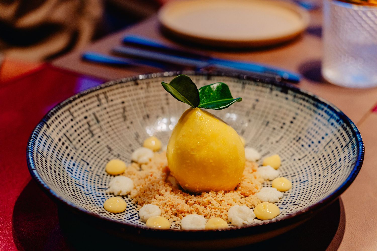 A series of elegant plated desserts featuring citrus and crumble elements arranged on textured ceramic dishes.