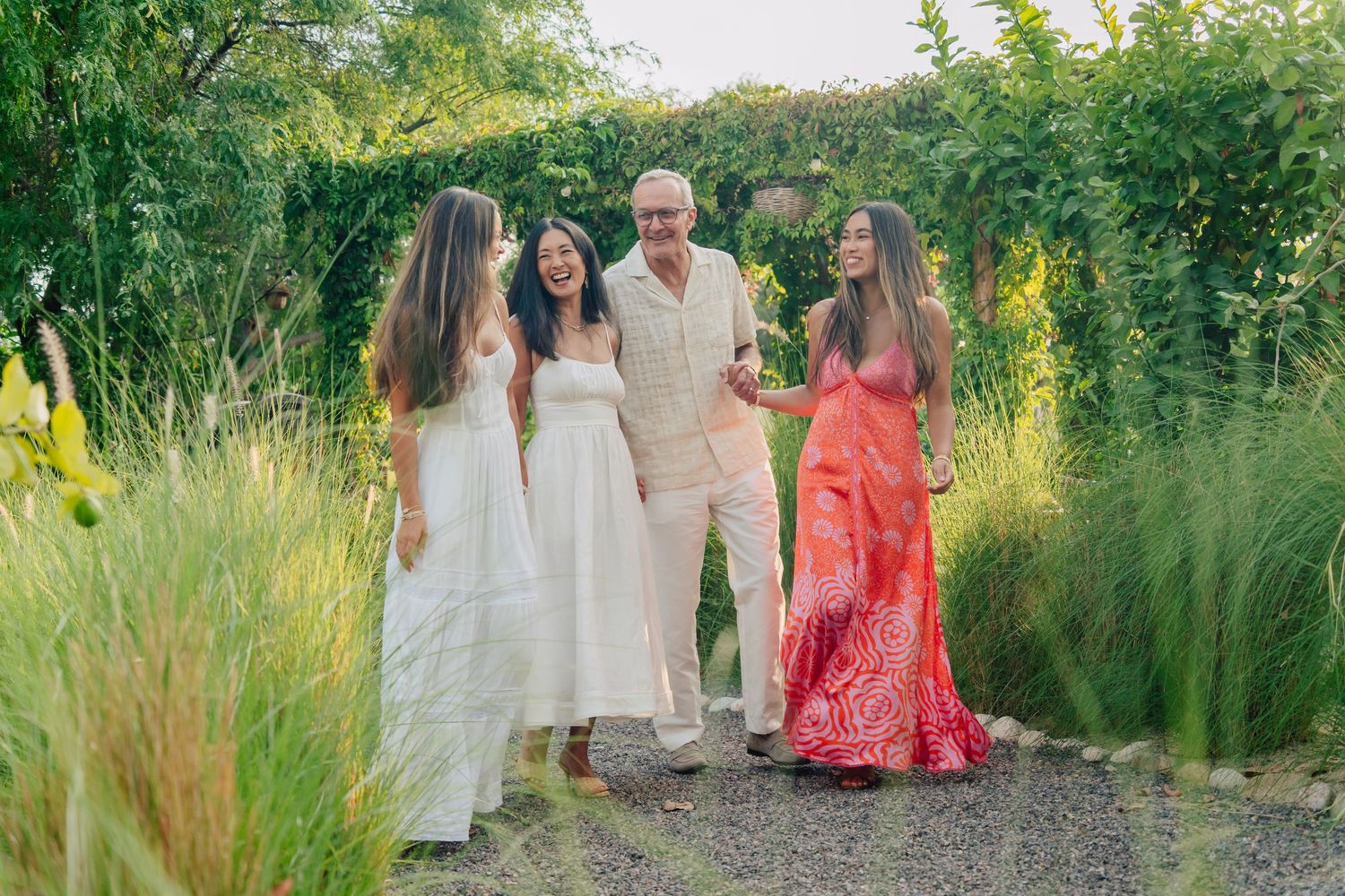 Group gathering in a lush garden setting wearing coordinated white and coral outfits.