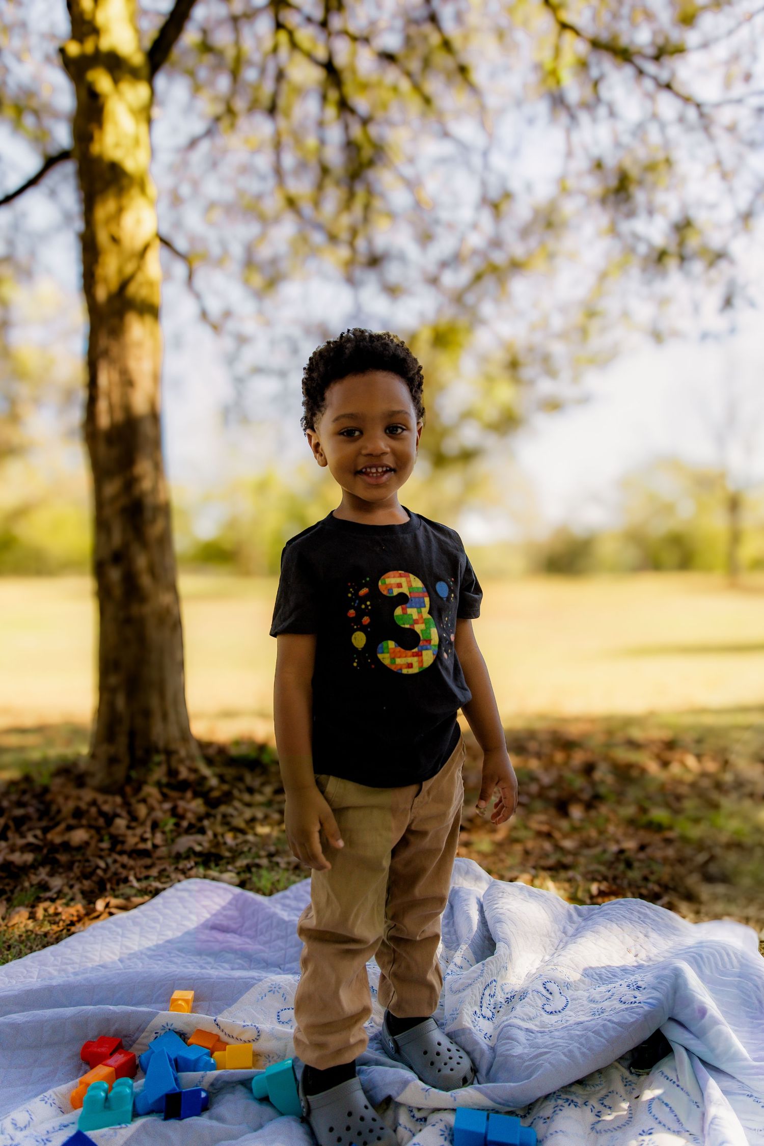 Boy standing on quilt with blocks smiling
