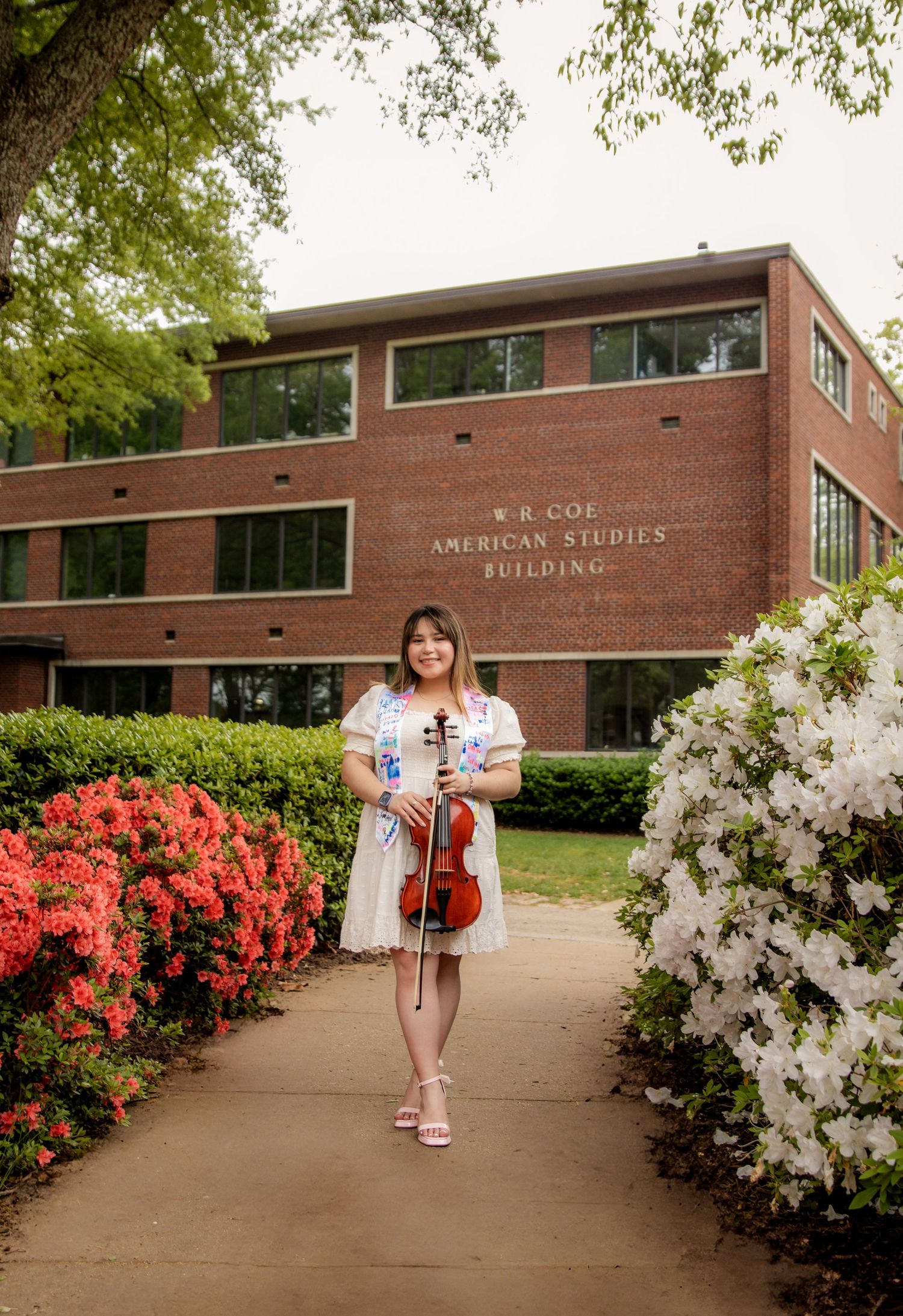 Girl with violin smiling at camera amongst pretty flowers