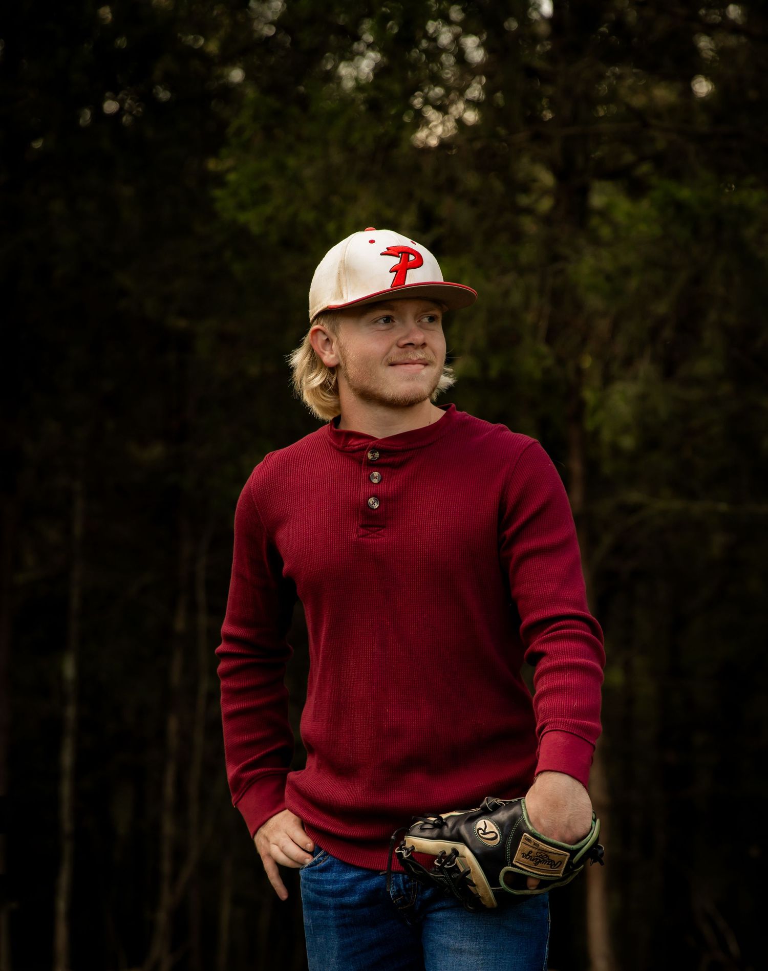 Boy with baseball glove and base ball hat smiling off