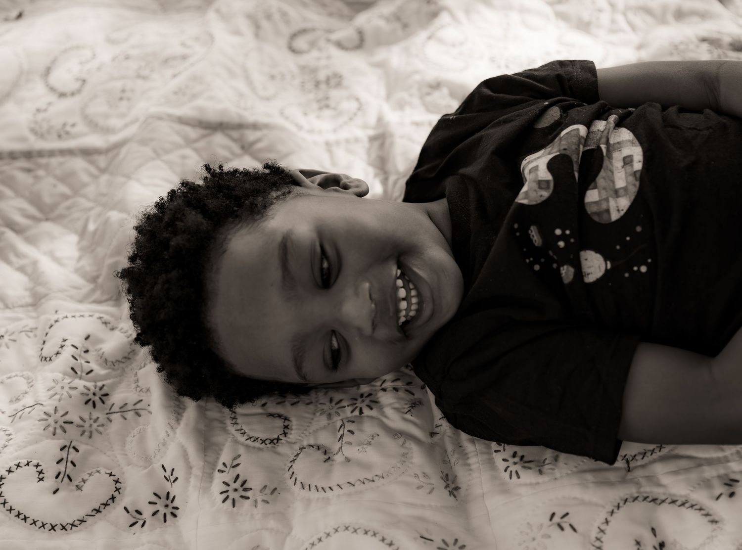 Black and White photo of a boy laying on quilt