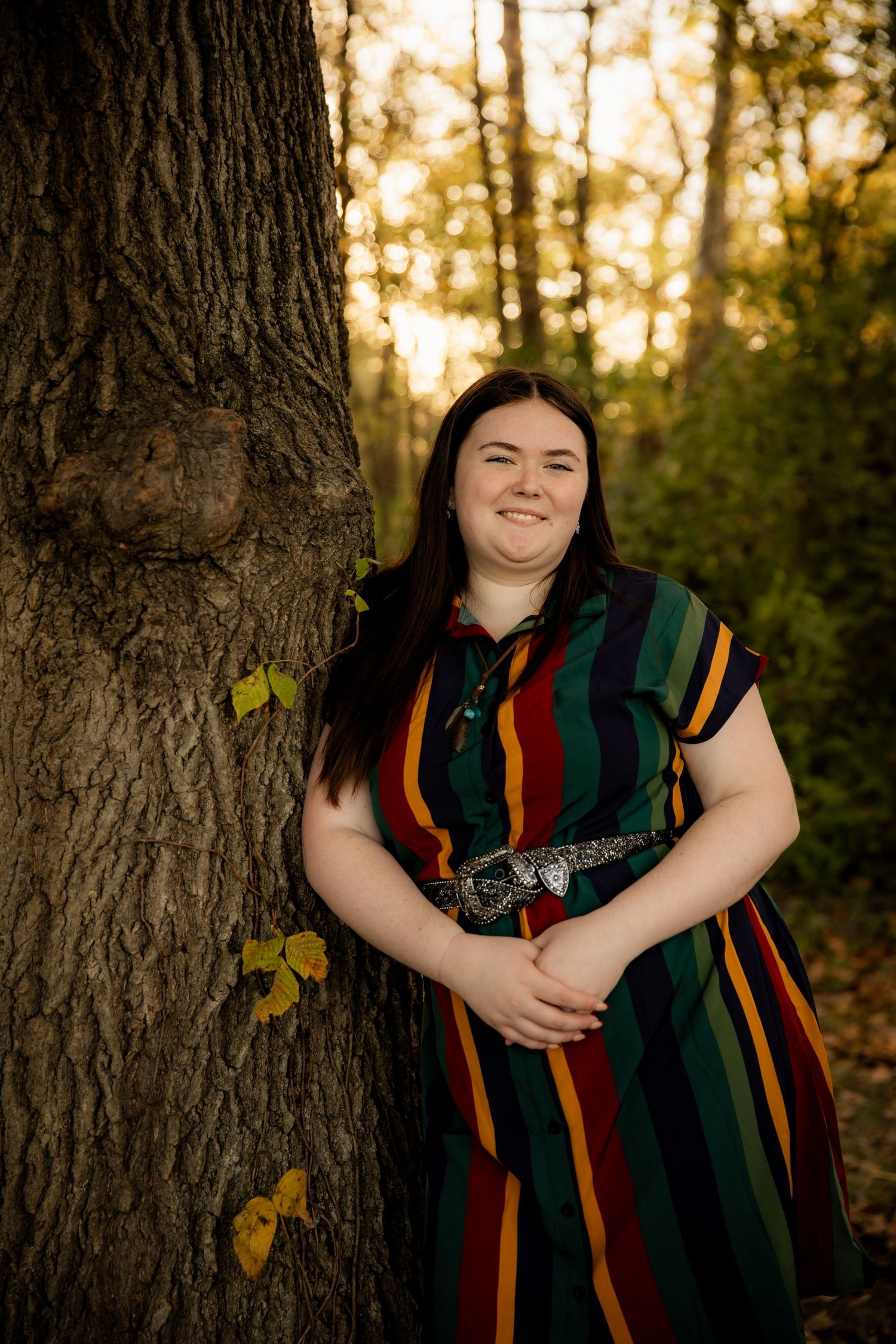 Girl leaning up against tree with arms crossed