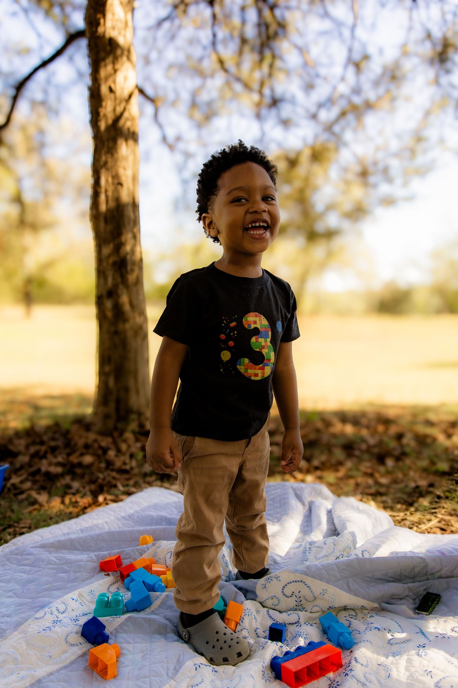 Boy standing on quilt with blocks laughing