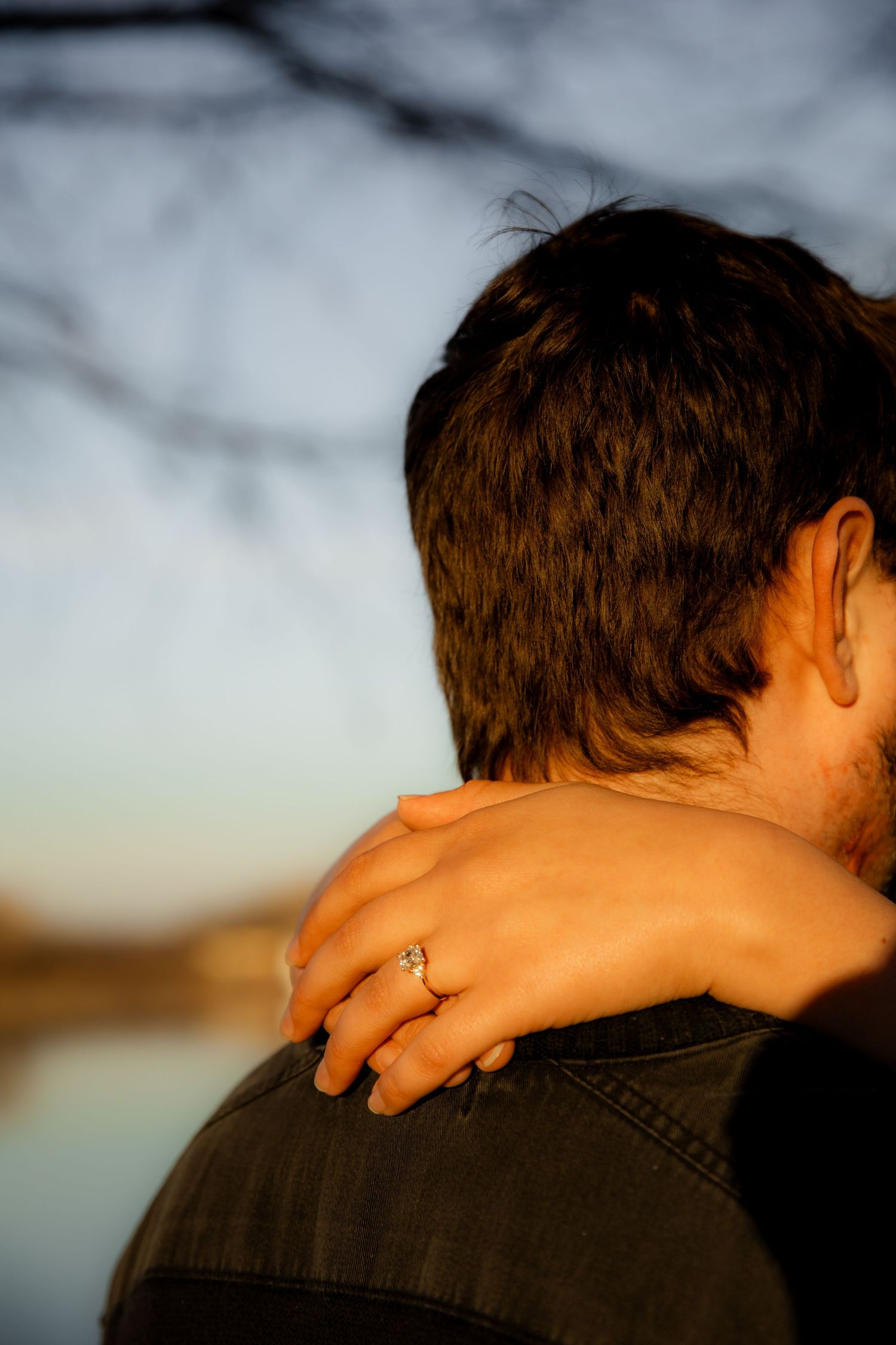 Showing off engagement ring behind boys neck