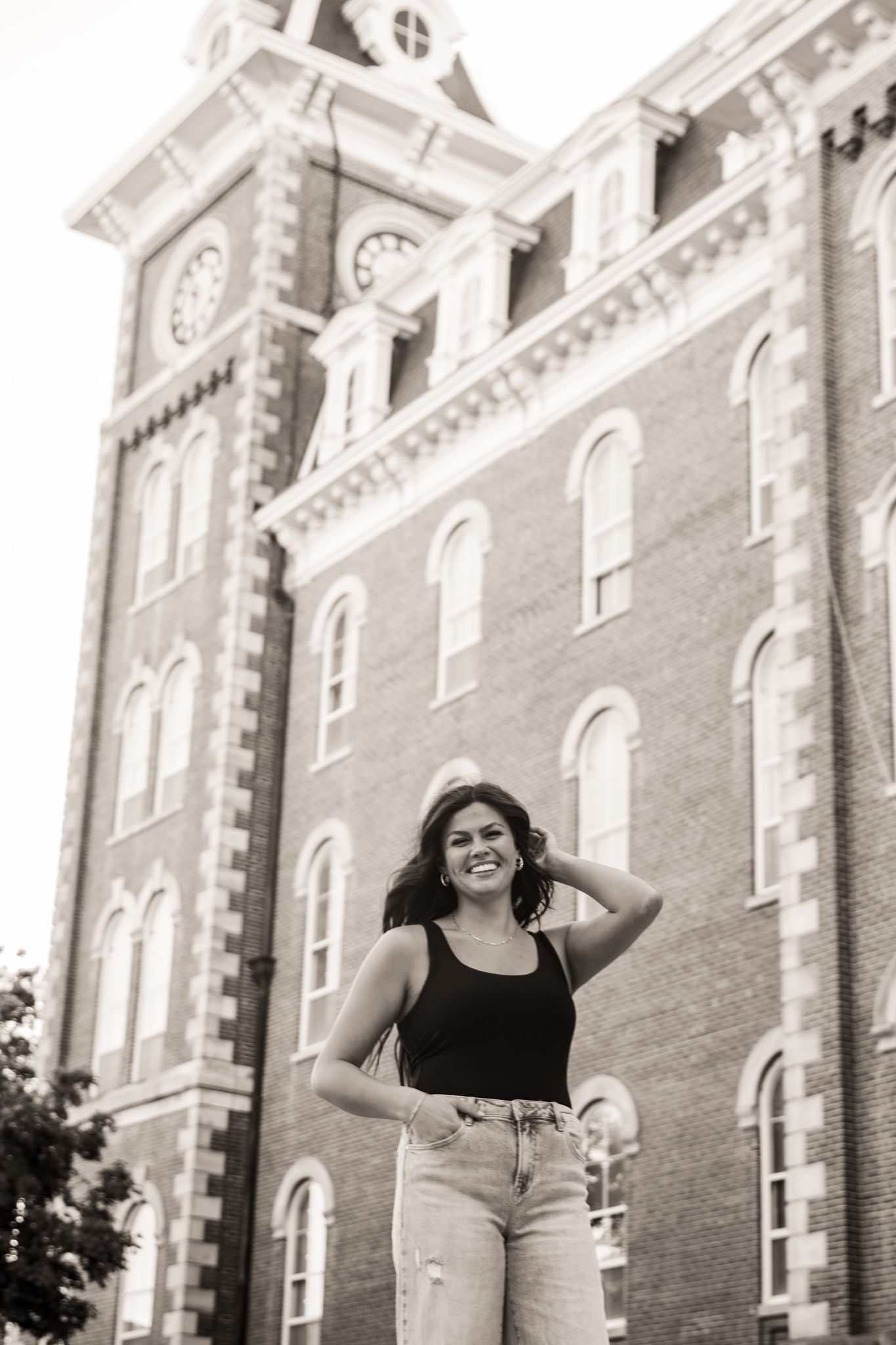 Senior posing with hand in hair in front of Old Main at University of Arkansas in black and white