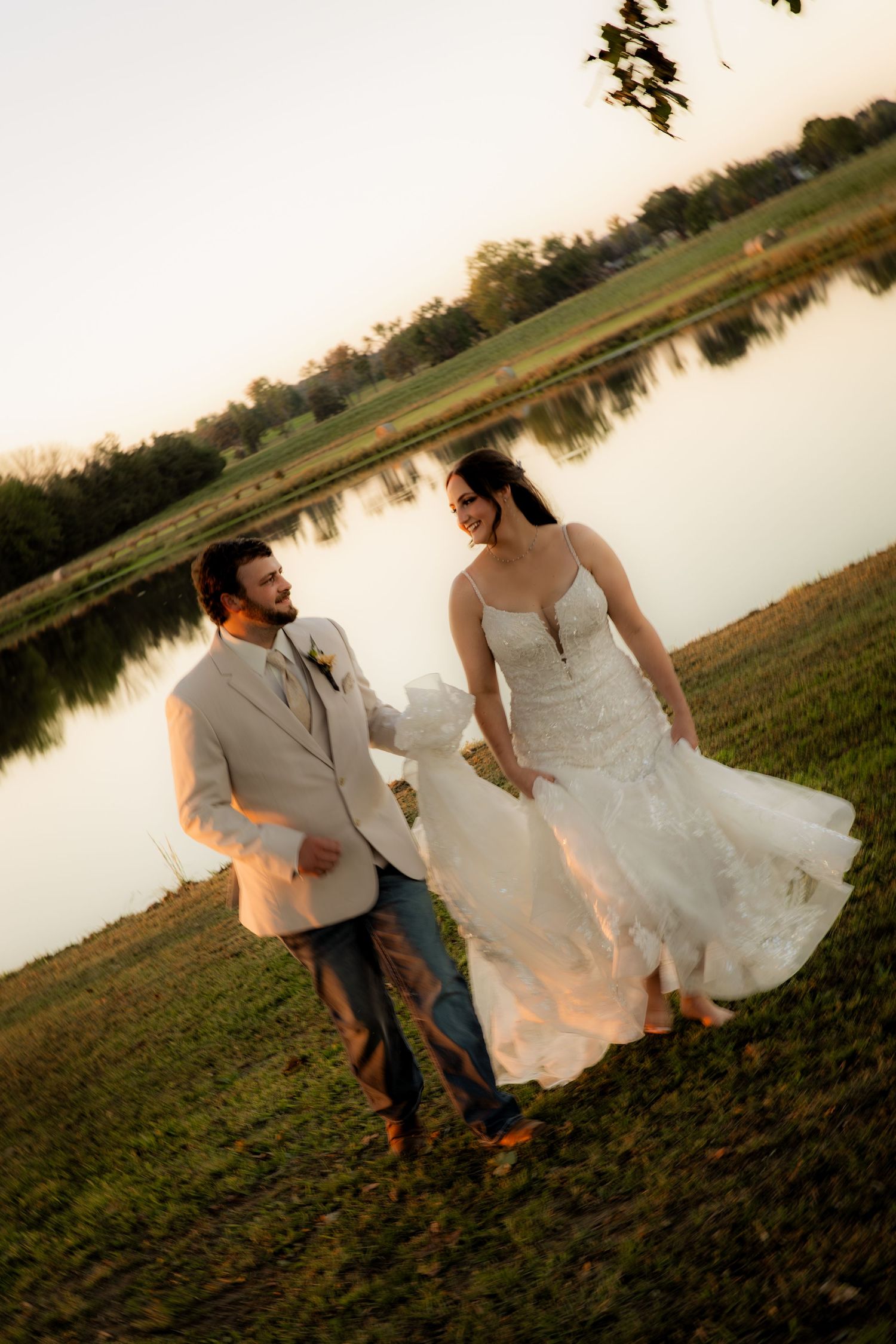 Husband holding wifes wedding dress smiling and walking and looking at each other