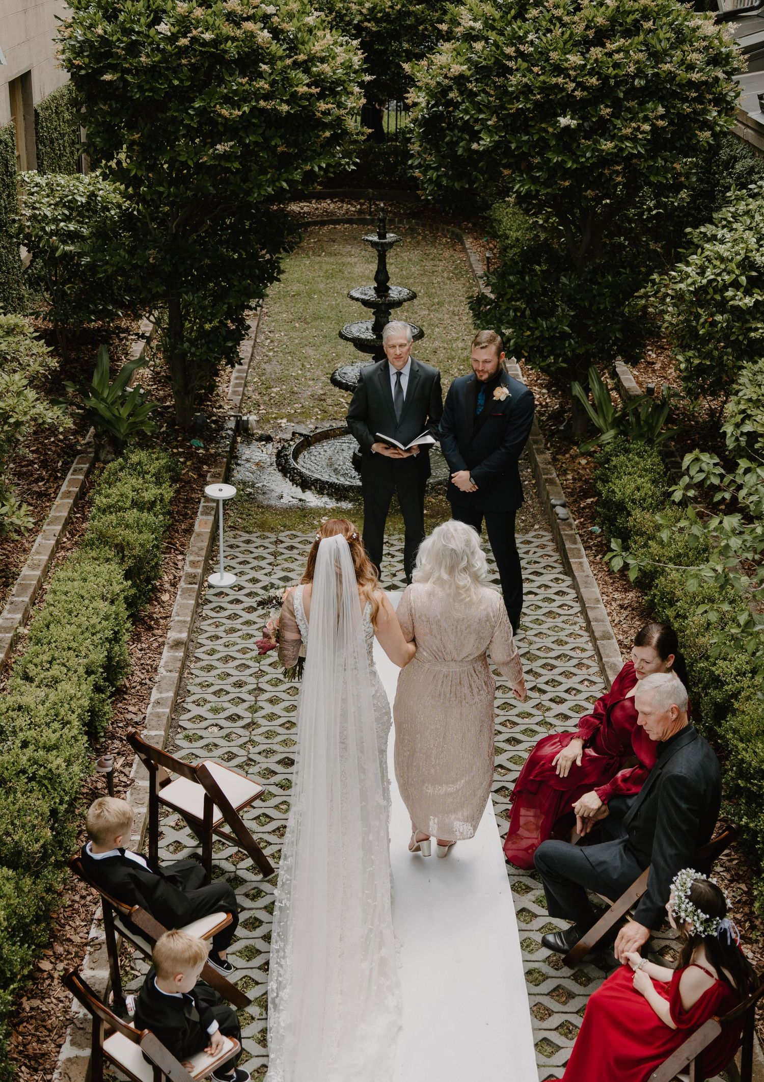 An overhead view of a wedding ceremony in a garden courtyard with stone pathways.