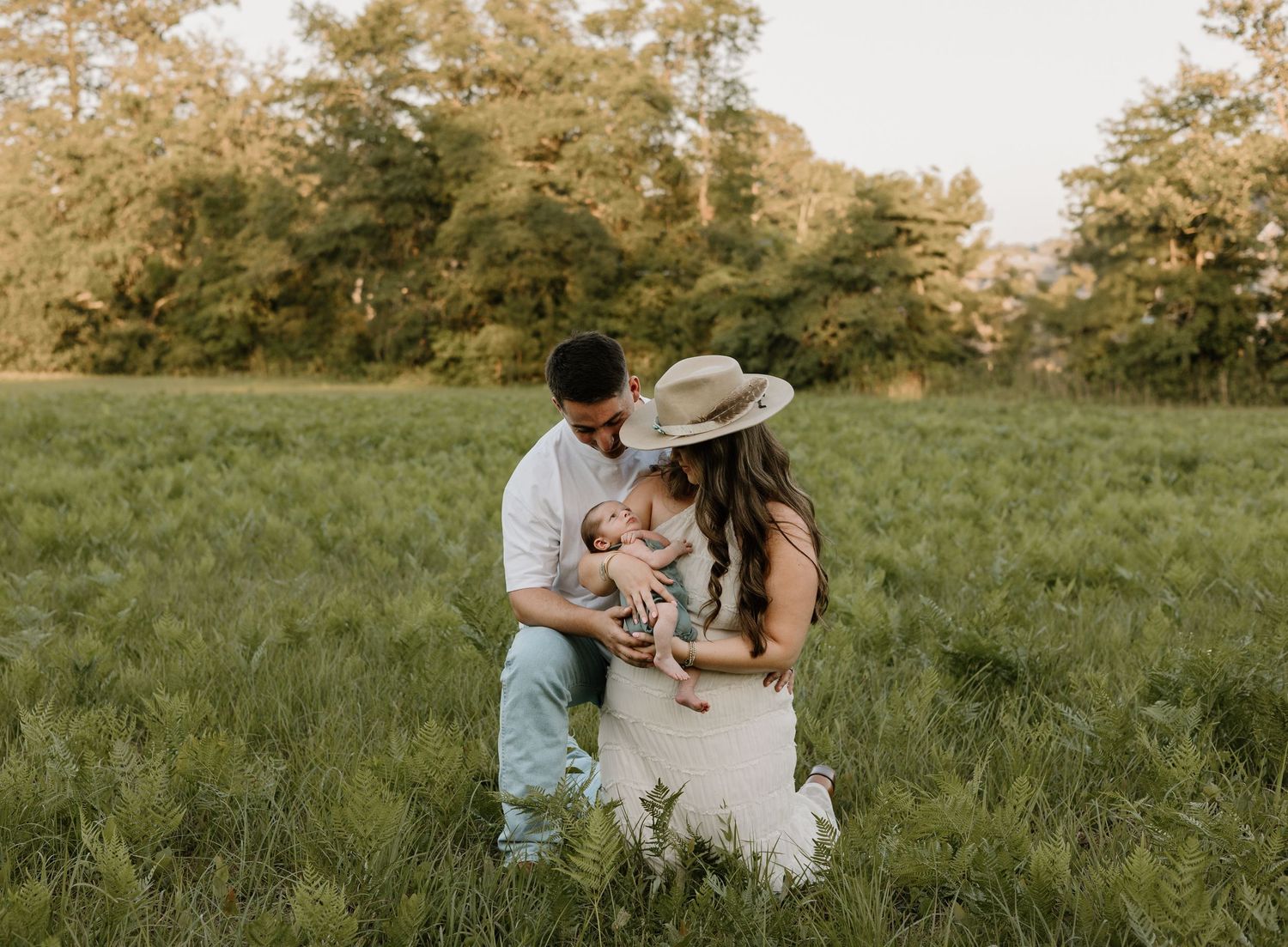Couple embraces in a sun-drenched grassy field during golden hour photo session.